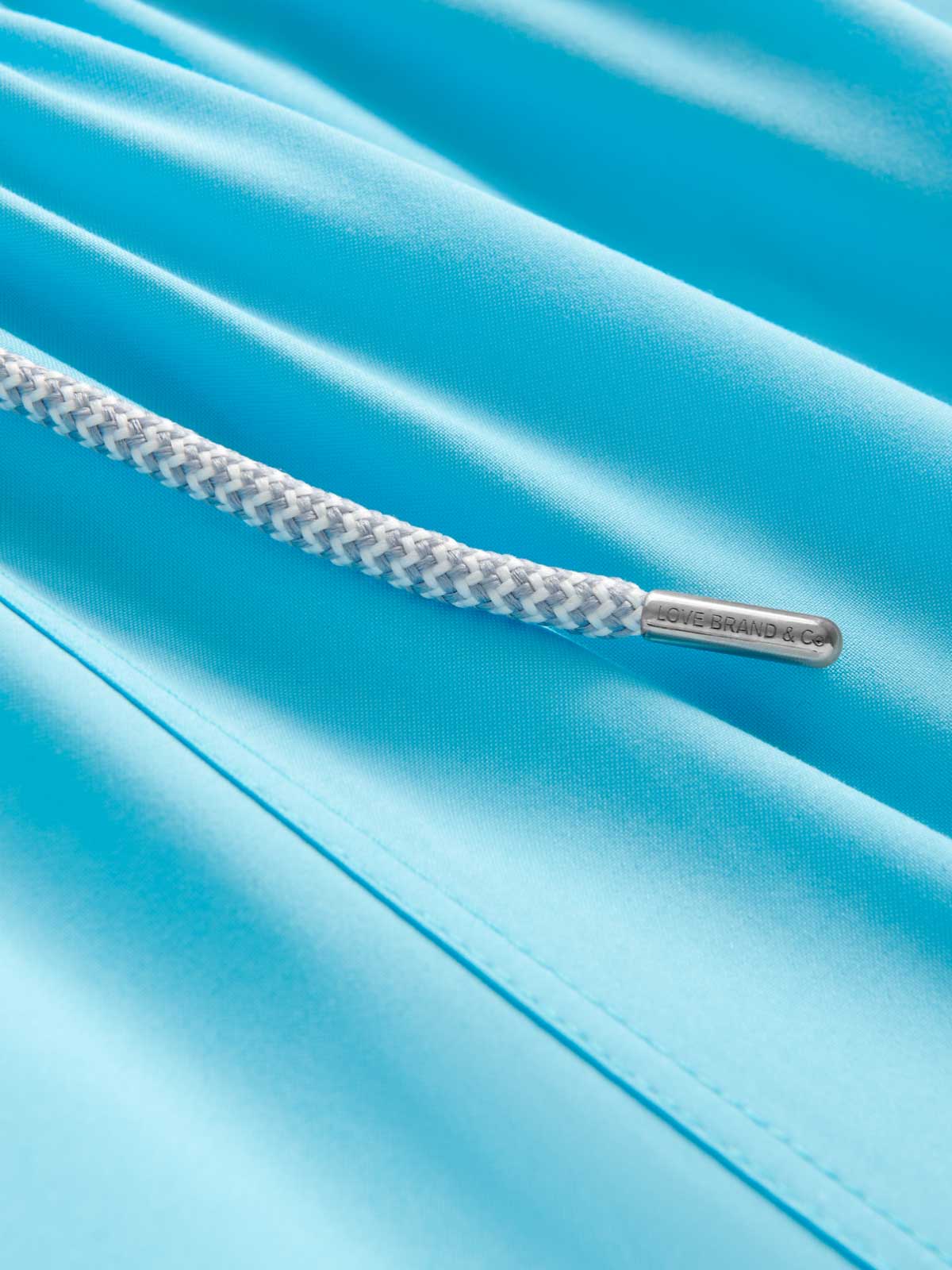 Close-up view of blue swimming trunks showcasing blue recycled fabric and drawstring.