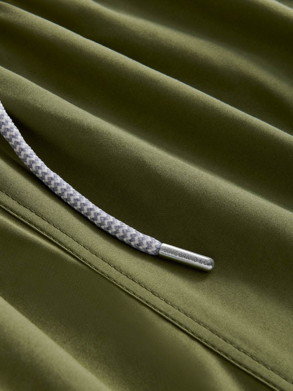 Close-up of a green swimming shorts fabric with drawstring detail.