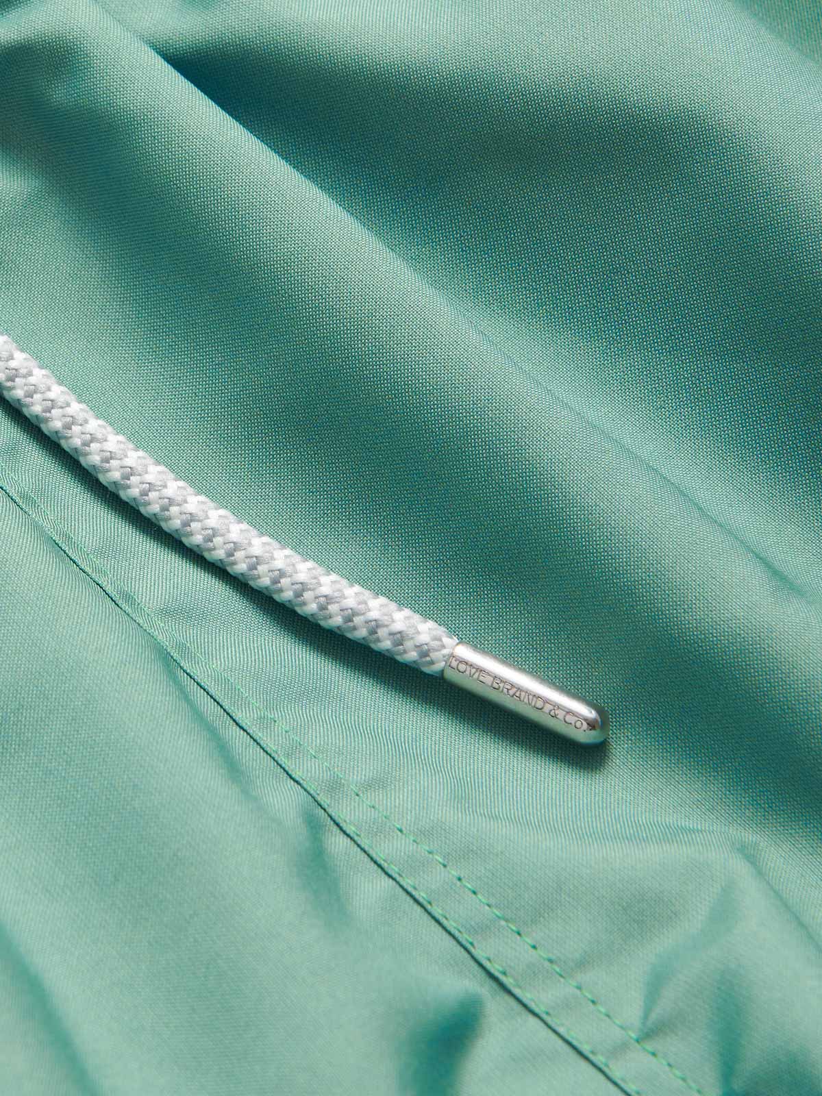 Close-up view of the drawstring and fabric of the Men's Riviera Green Staniel Swim Shorts. Plain swim shorts crafted from 100% recycled quick-dry material.
