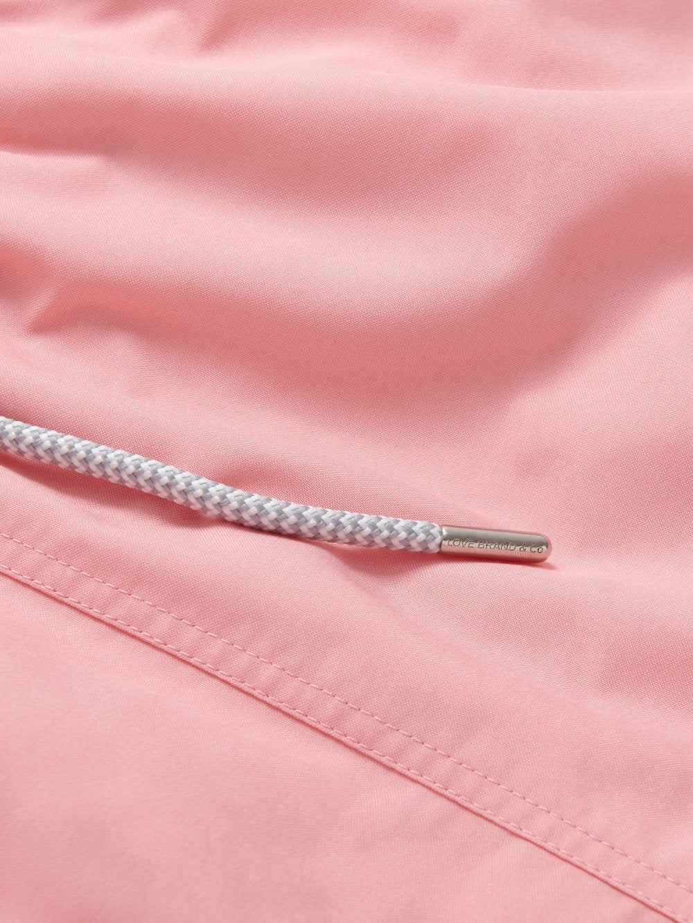 Men's Pastel Pink Staniel Swim Shorts. Plain pink swim shorts close-up image showcasing stitching and drawstring.