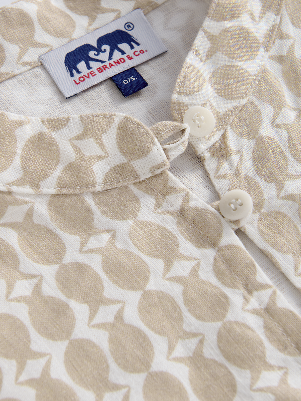 Close-up of a beige poncho with a love brand brand label and pineapple pattern