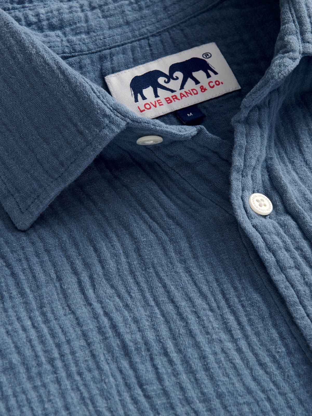 Close-up of a blue cotton waffle shirt with a brand label on the collar.