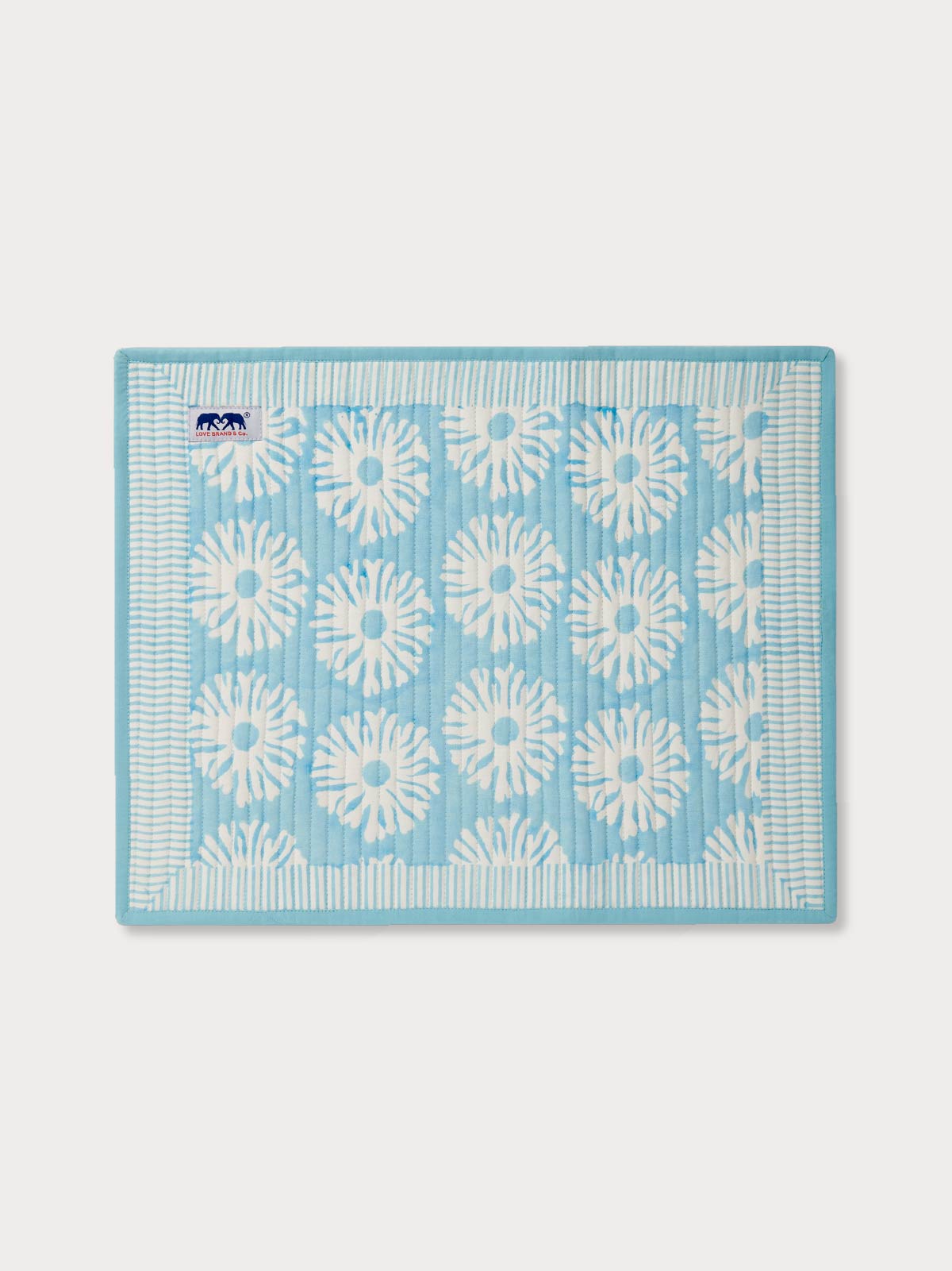Blue placemat with white coral pattern on a light grey background