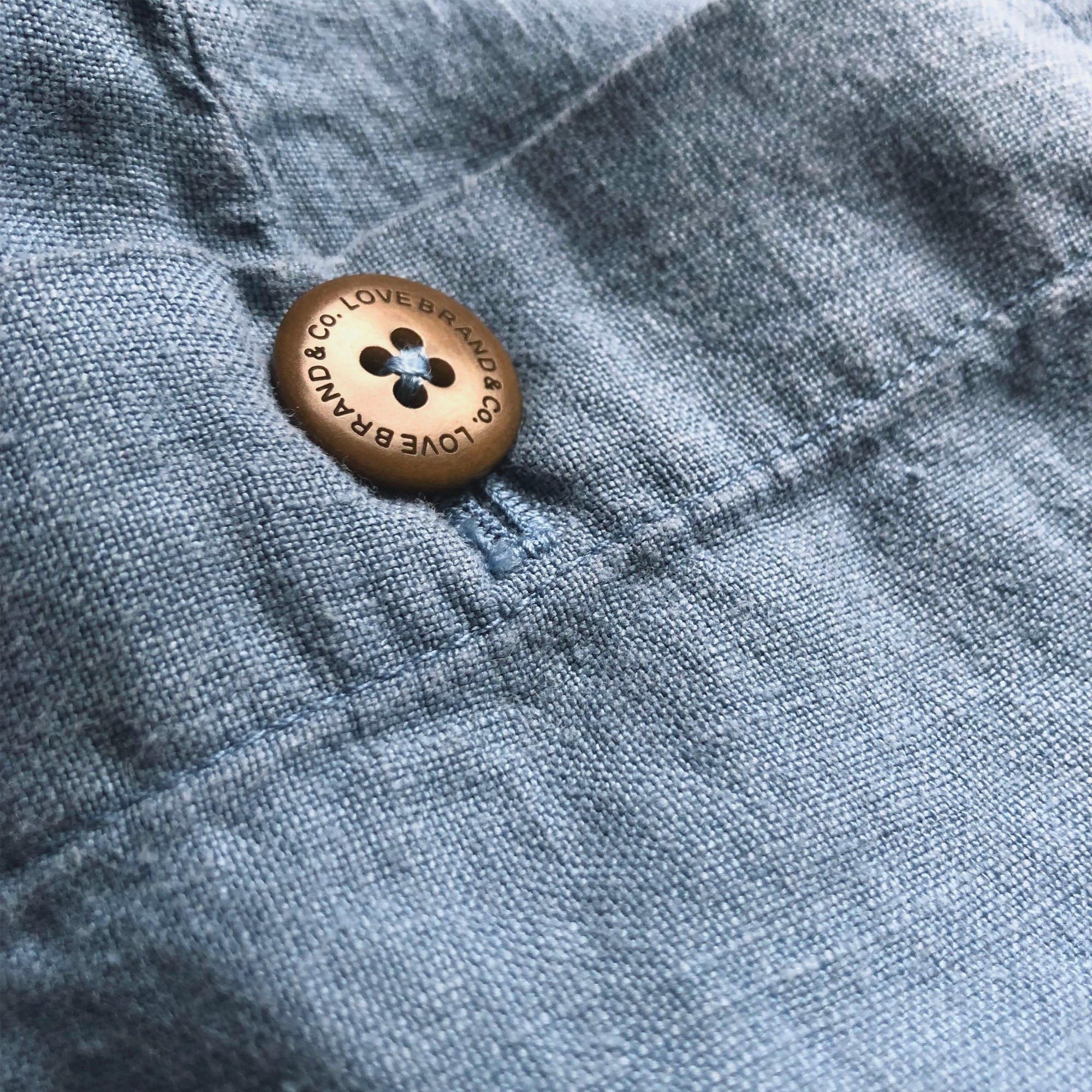 Close-up of Men's French Blue Burrow Linen Shorts showcasing a distinct dusty blue color and a button detail.