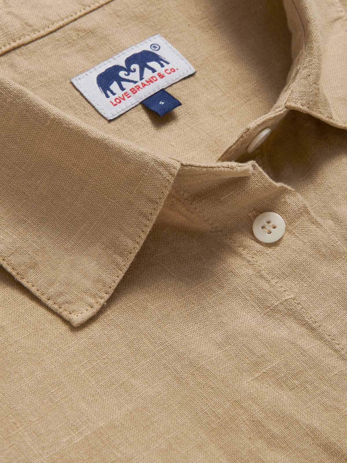Close-up view of beige midaxi linen shirt dress with long sleeves and a front pocket.