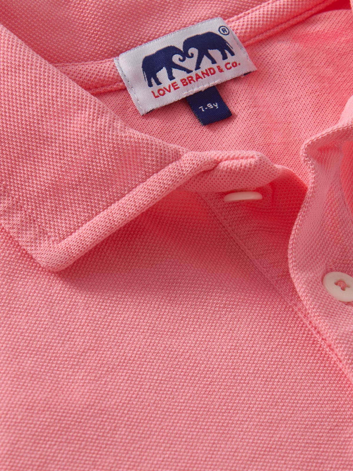 Children's pink polo shirt on a light background.