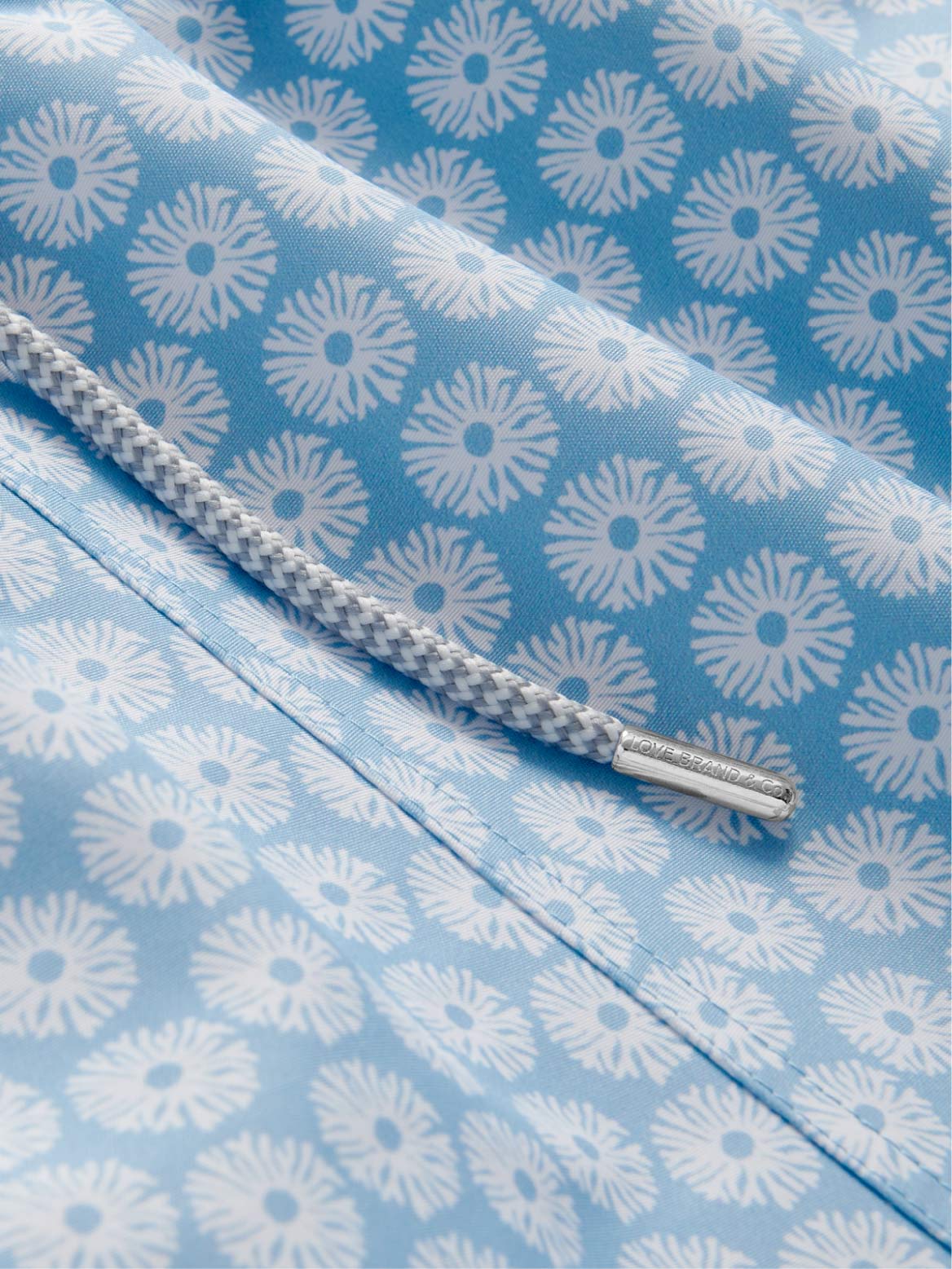 Close-up of a blue swim trunks fabric with white coral pattern and a drawstring