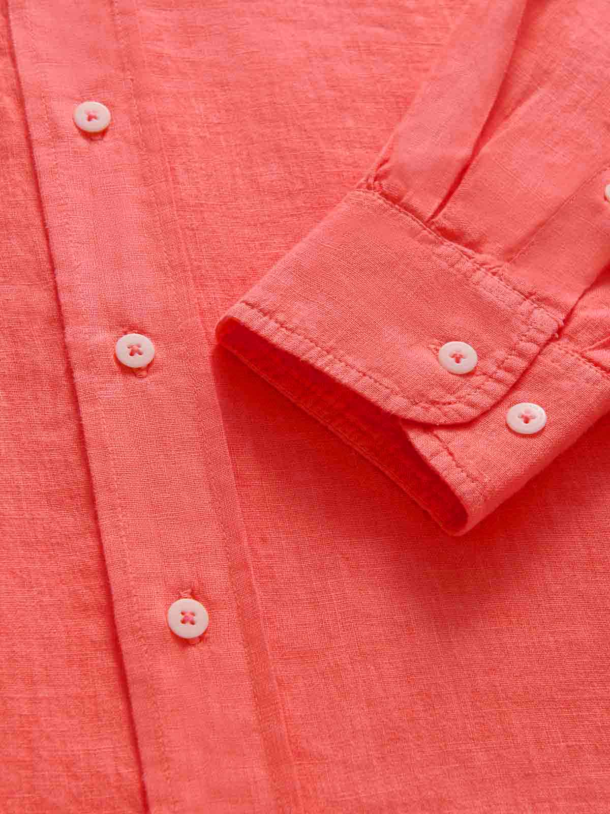 Close-up of a coral pink button-up shirt with rolled-up sleeve.