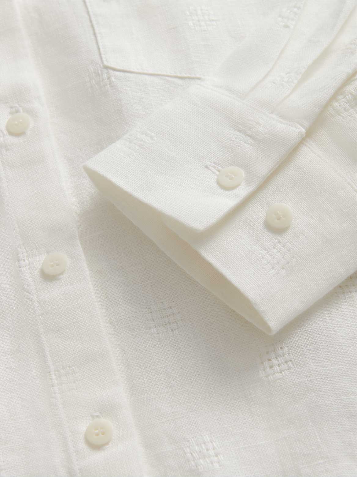 Close-up of a cream textured shirt with buttons.