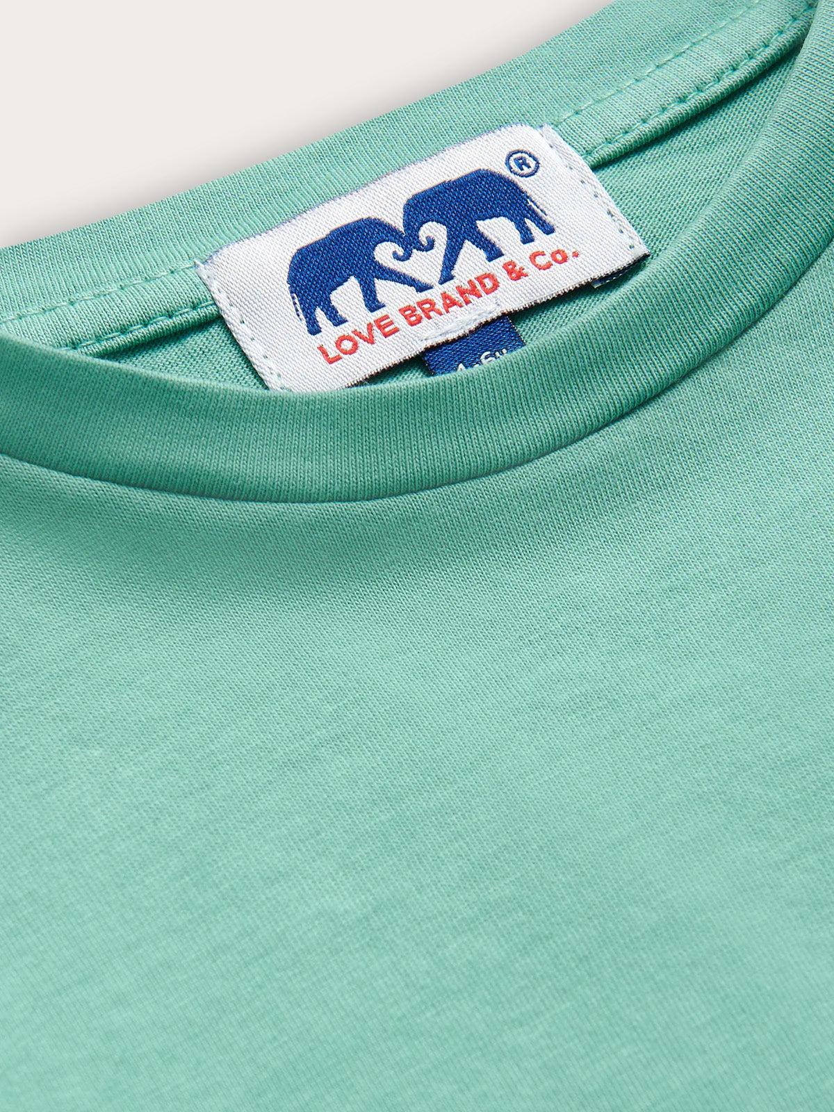 Close-up of a teal shirt with a visible brand label featuring two elephants.