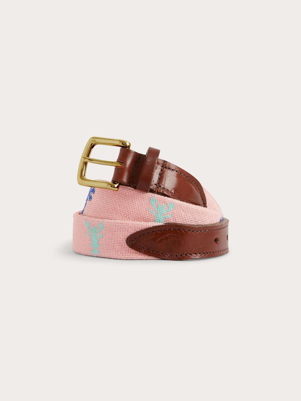 A pink woven canvas belt with a brown leather strap, gold buckle, and light blue embroidered monogram details, shown on a light gray background.