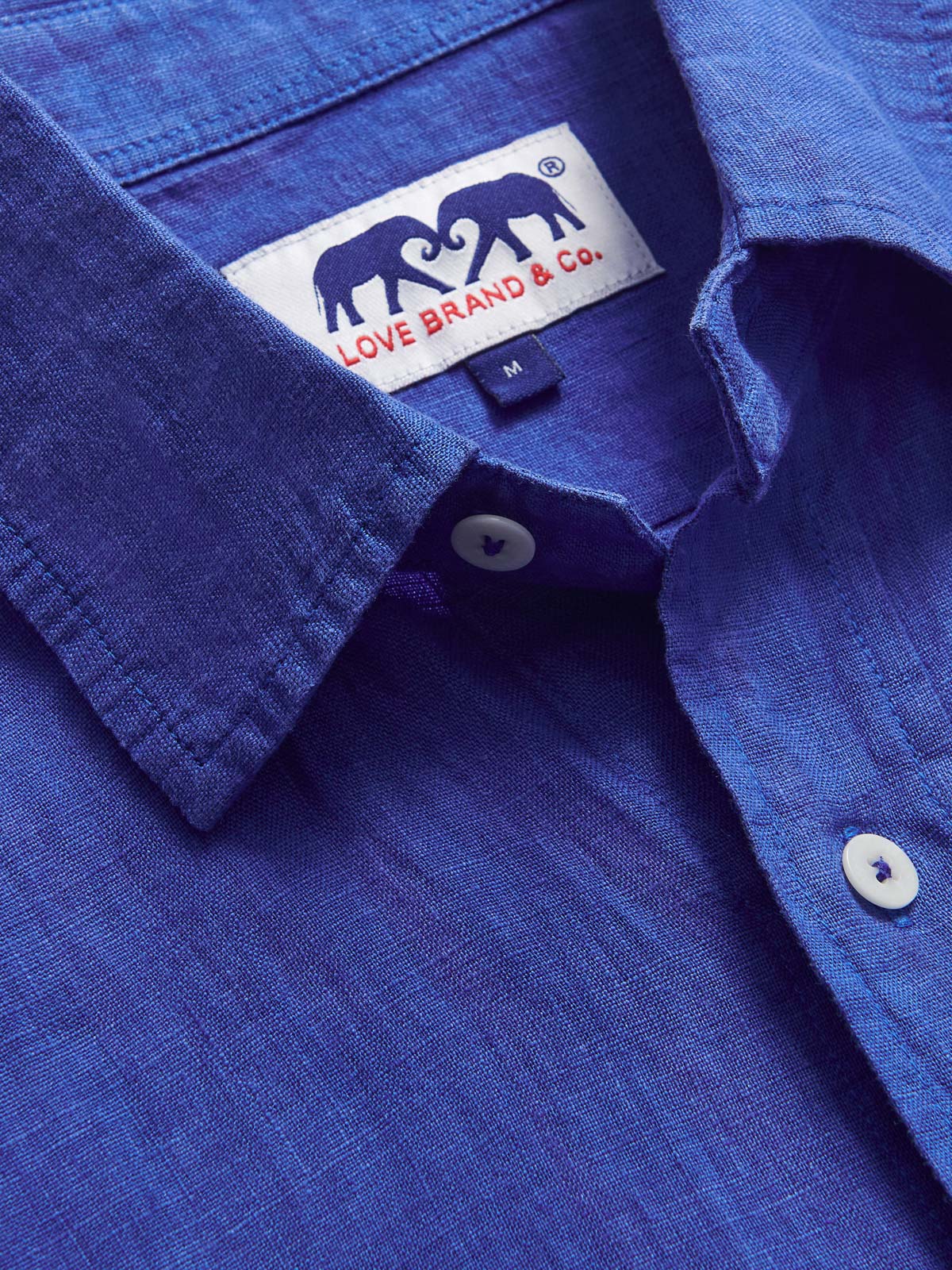 Close-up view of the collar of Men's Majorelle Blue Abaco Linen Shirt. Linen men's shirt in blue showcasing love brand & co. logo.