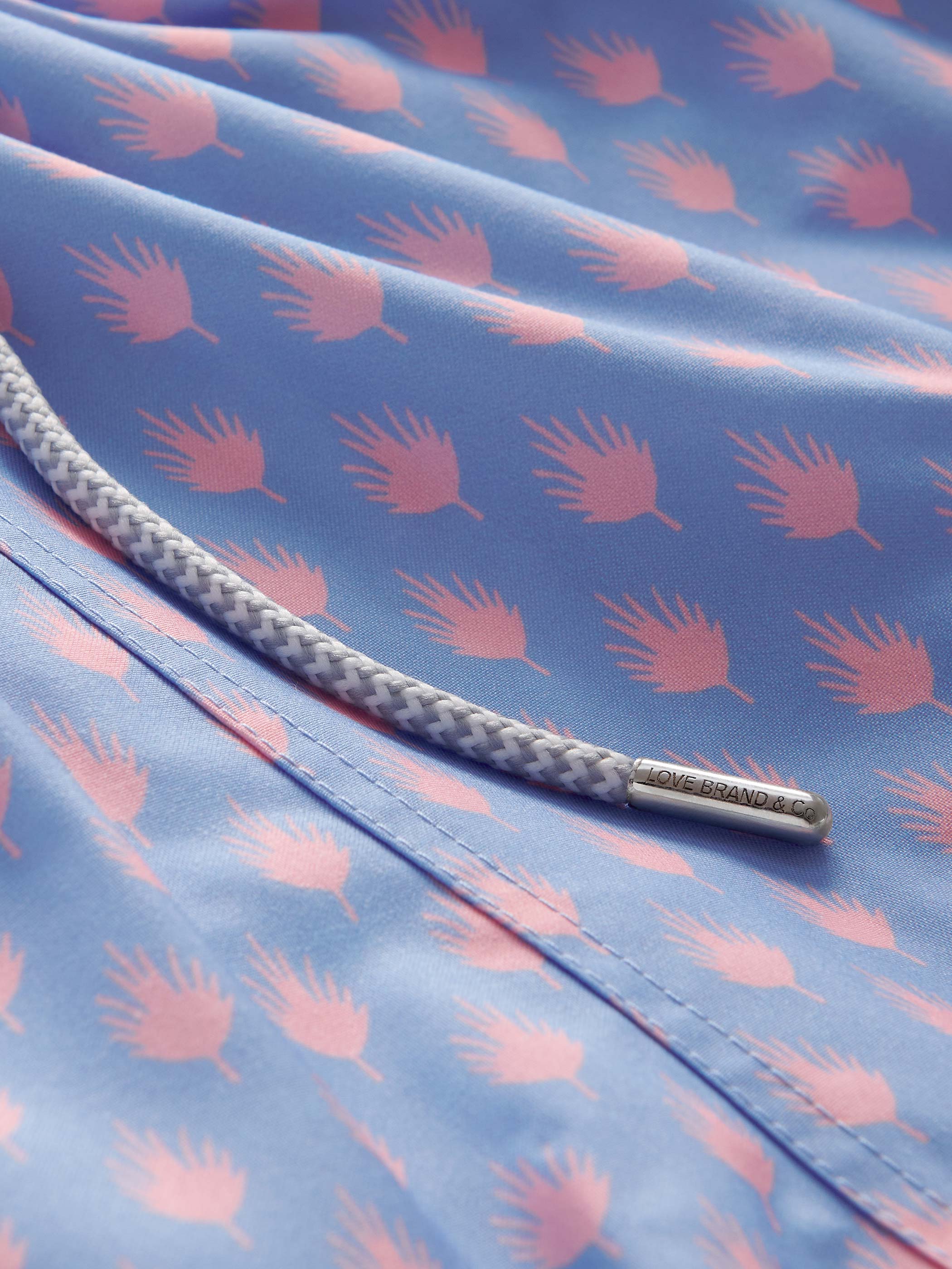Close-up of a blue fabric with pink leaf pattern and braided drawstring.