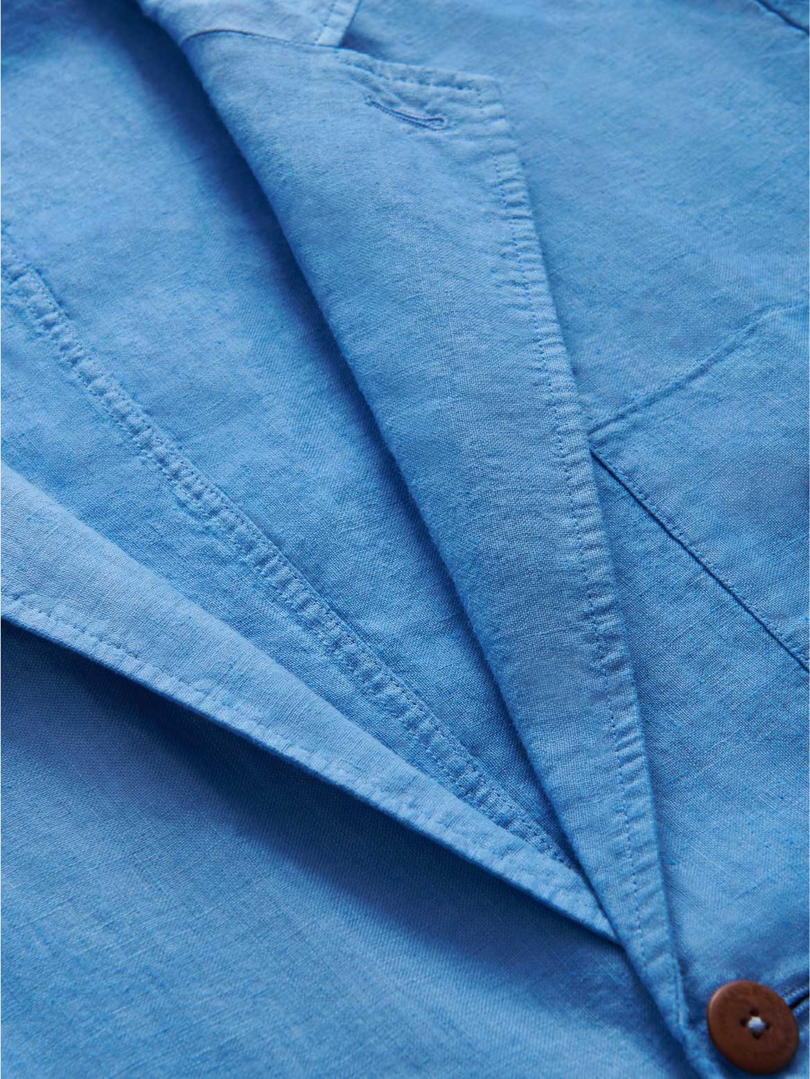 Close-up of a blue linen jacket with a button.