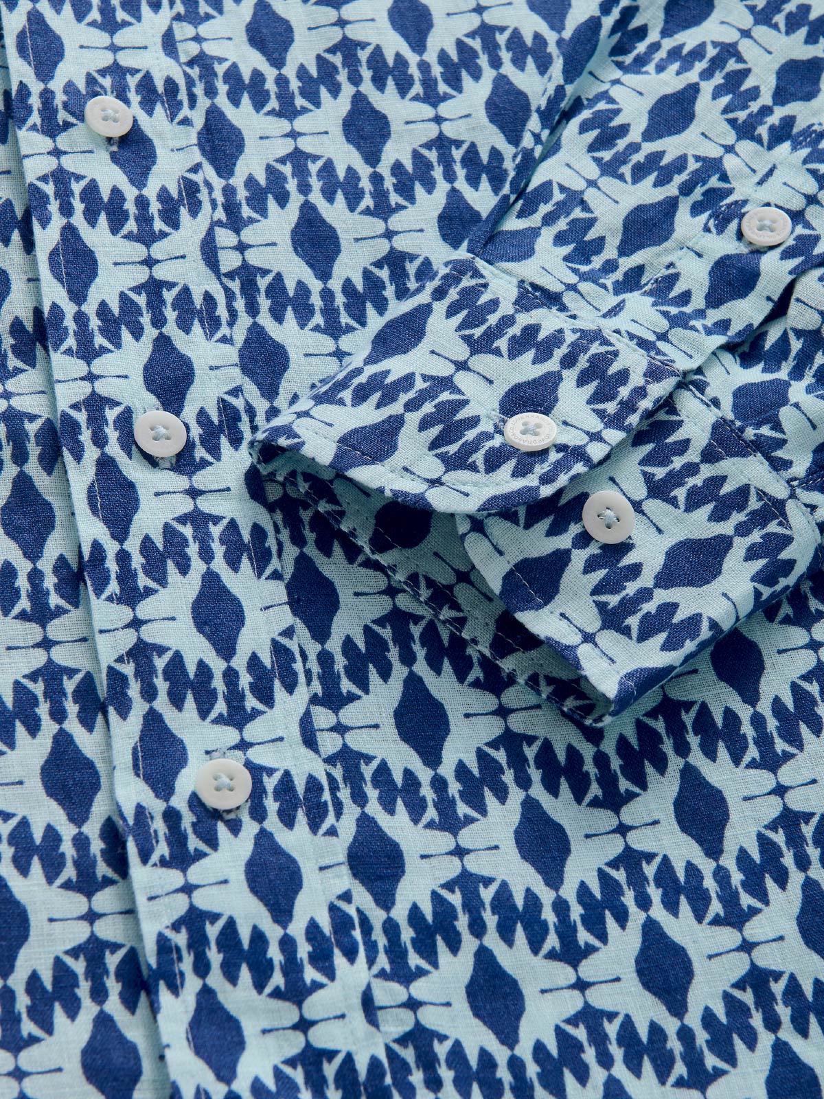 Close-up of a blue and white patterned shirt with button details.