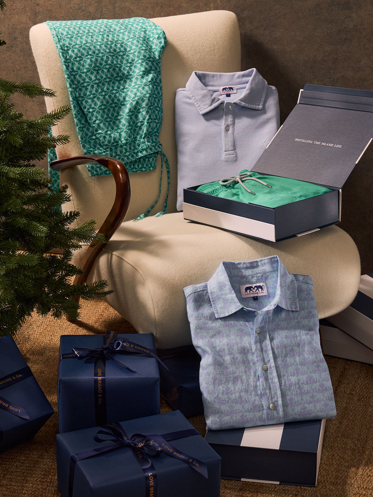 Gifts and clothing items on a couch with a Christmas tree in the background
