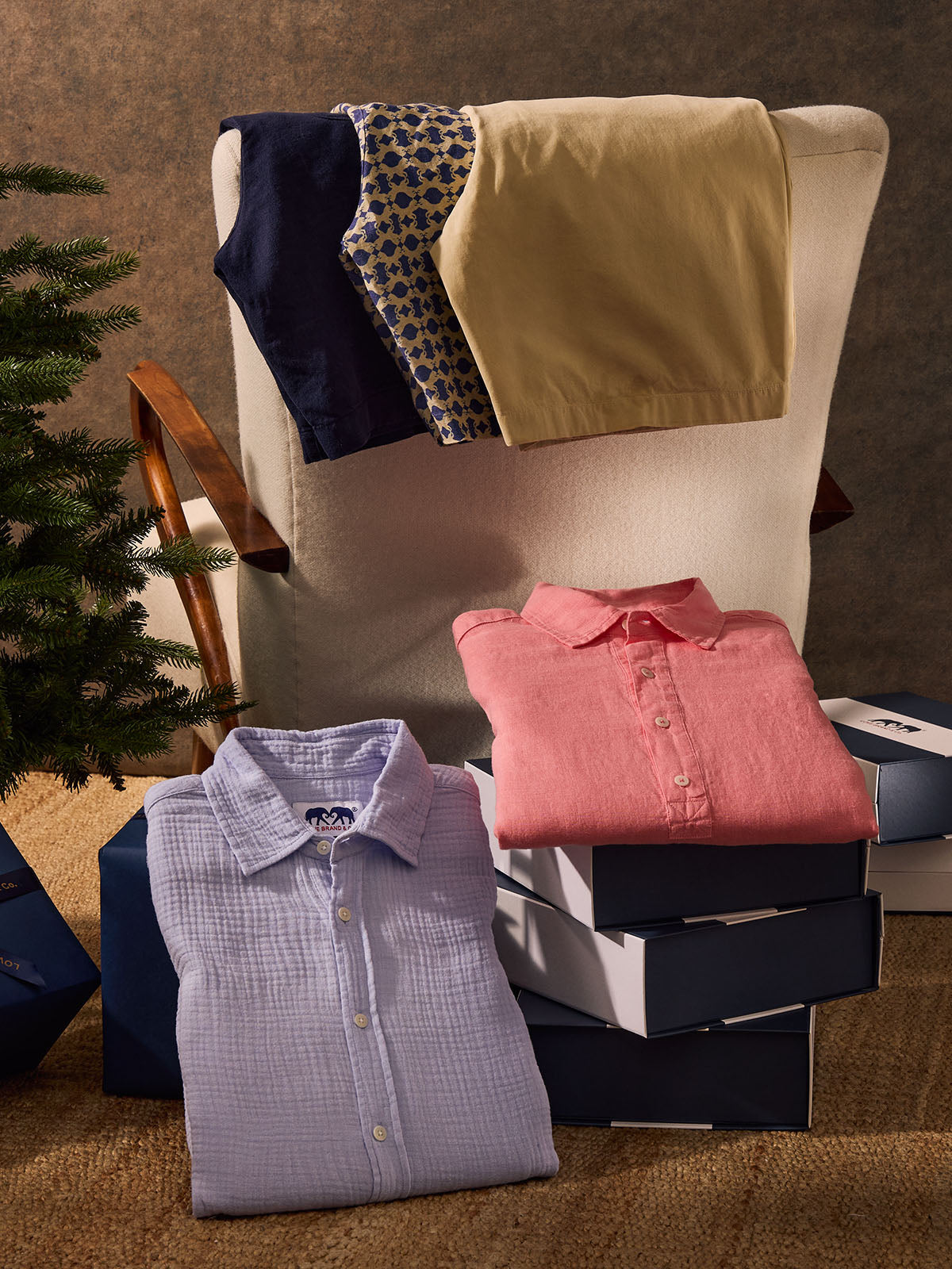 Folded shirts on a chair and stack with a Christmas tree in the background
