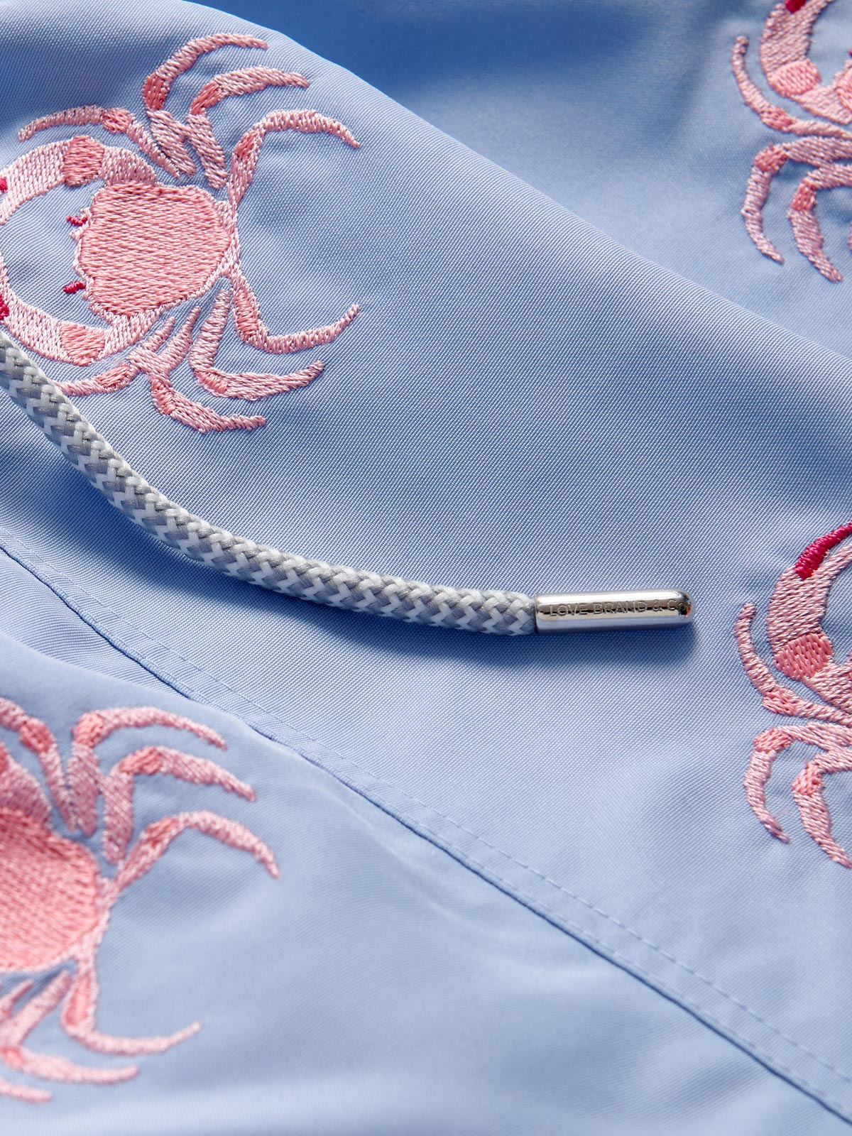 Light blue fabric with pink crab embroidery and a white drawstring detail.