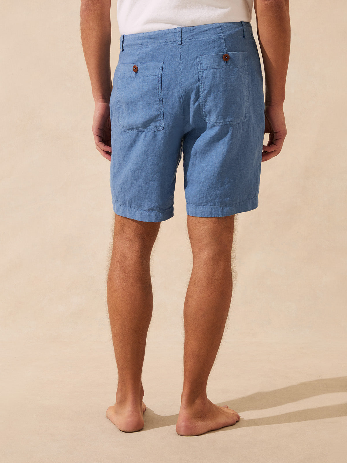 Person wearing blue shorts on a beige background