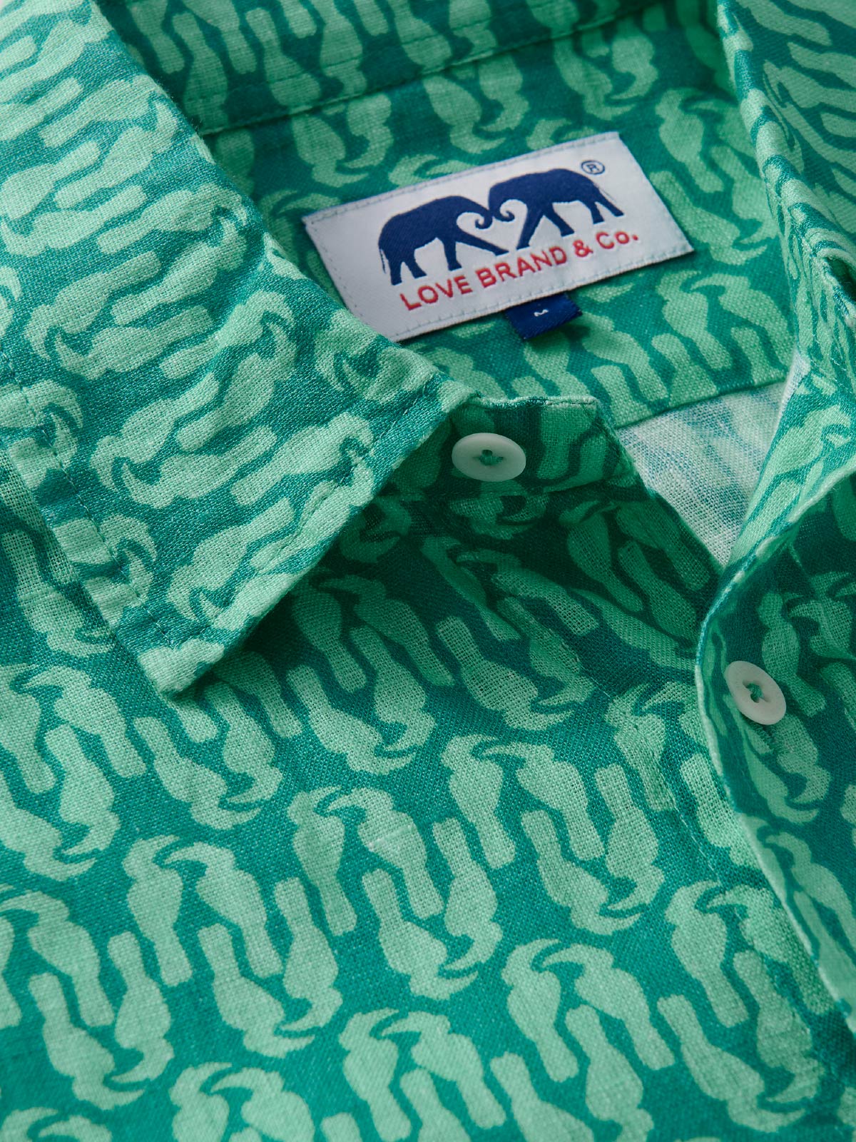 Close-up of a green patterned shirt with a visible love brand label.
