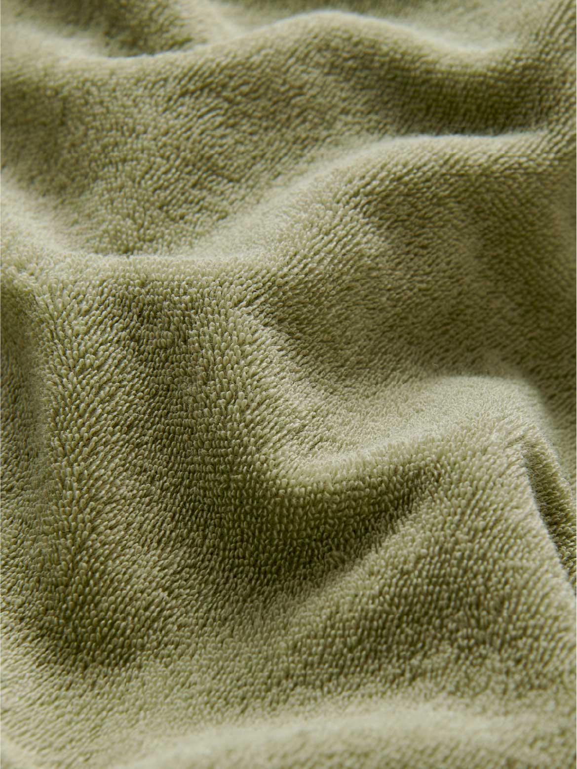 Close-up texture detail of olive green terry towelling fabric.