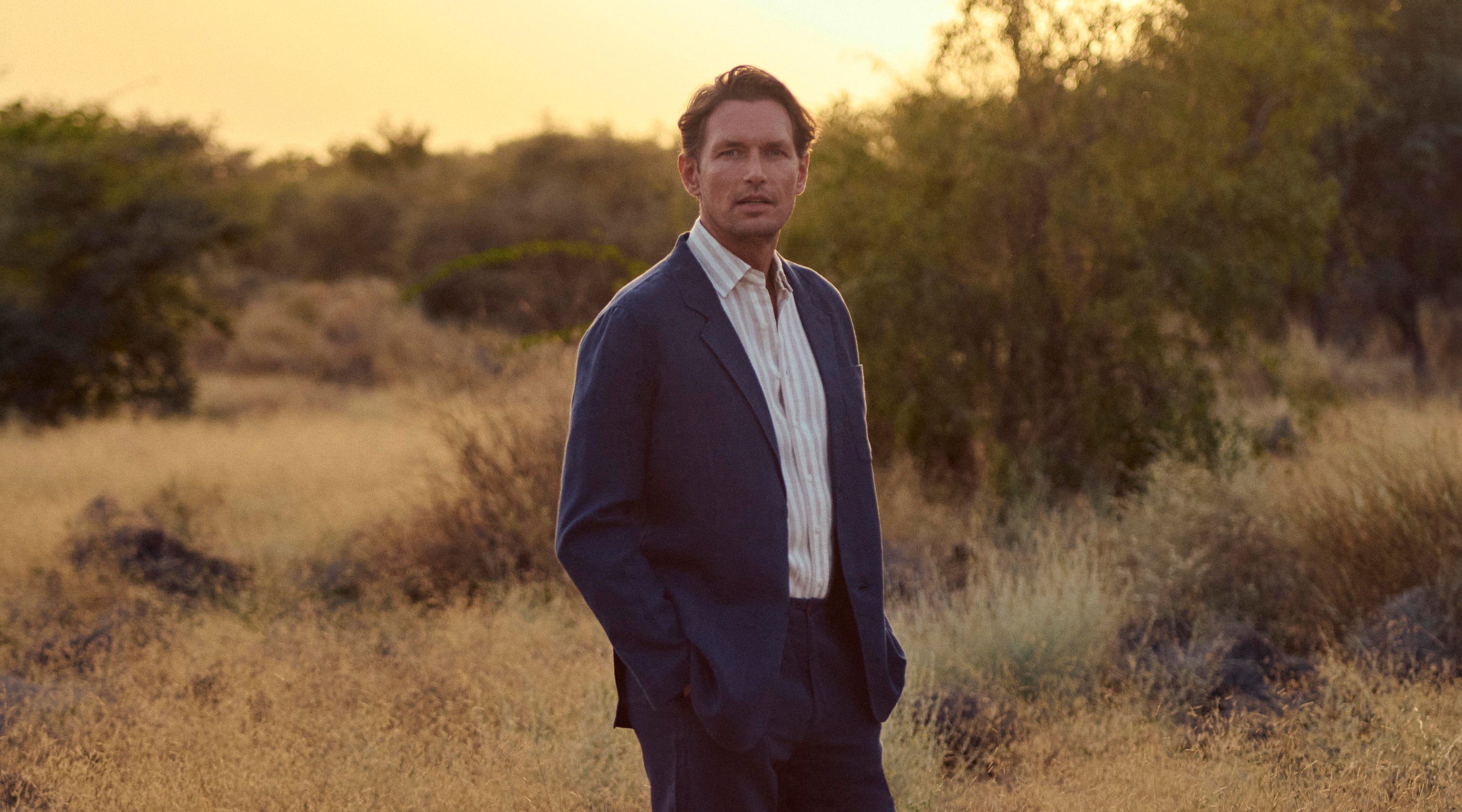 Man in a blue linen summer jacket for men standing in a desert landscape with a warm glow