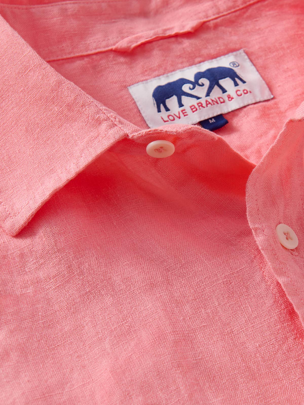 Close-up of a pink linen shirt with a visible love brand label.