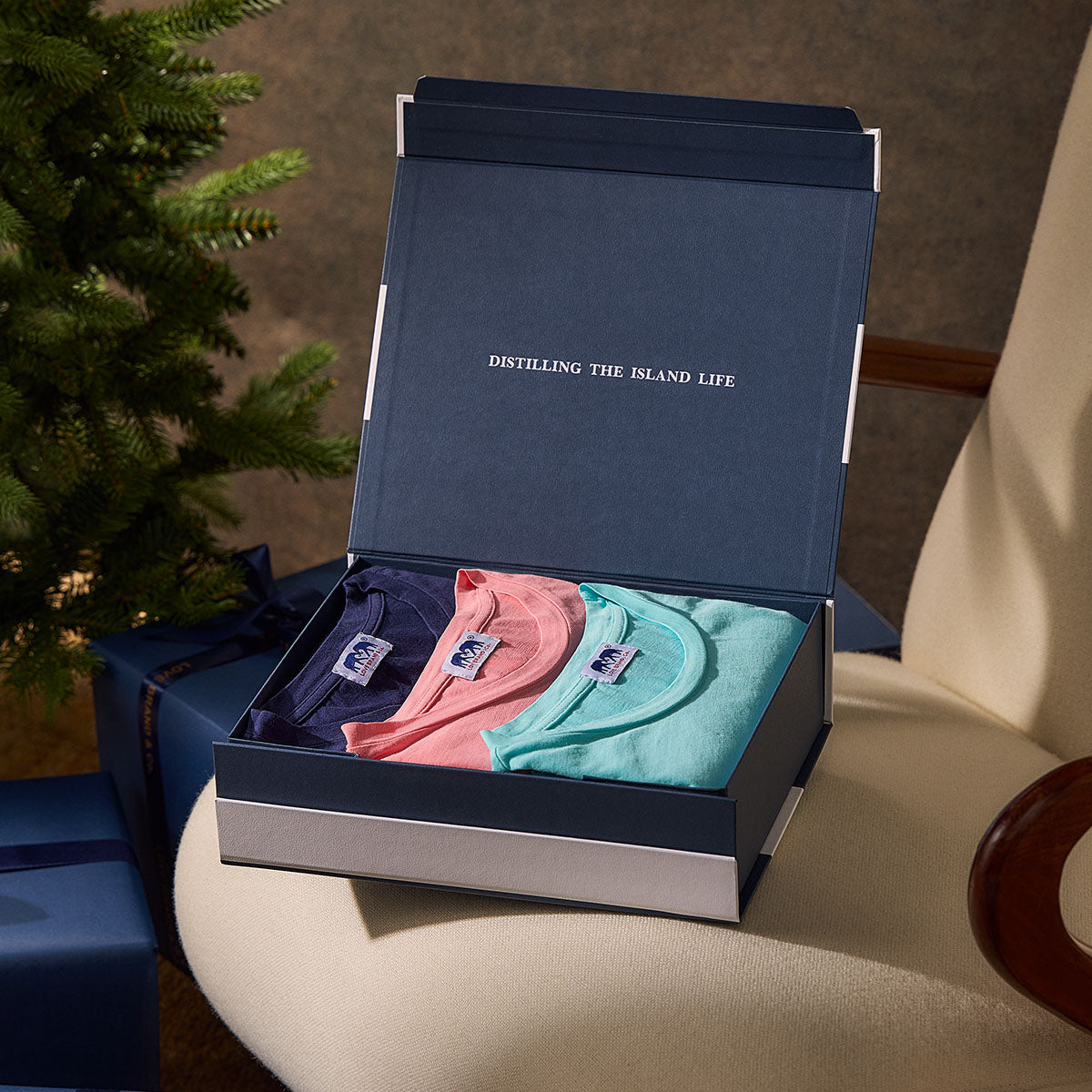 Open box containing three colourful t-shirts.