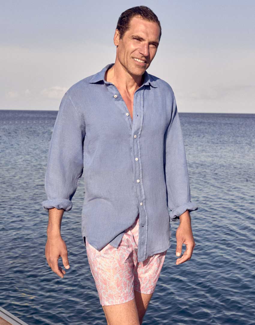Model wears blue linen shirt and Crazy Coral swim shorts
