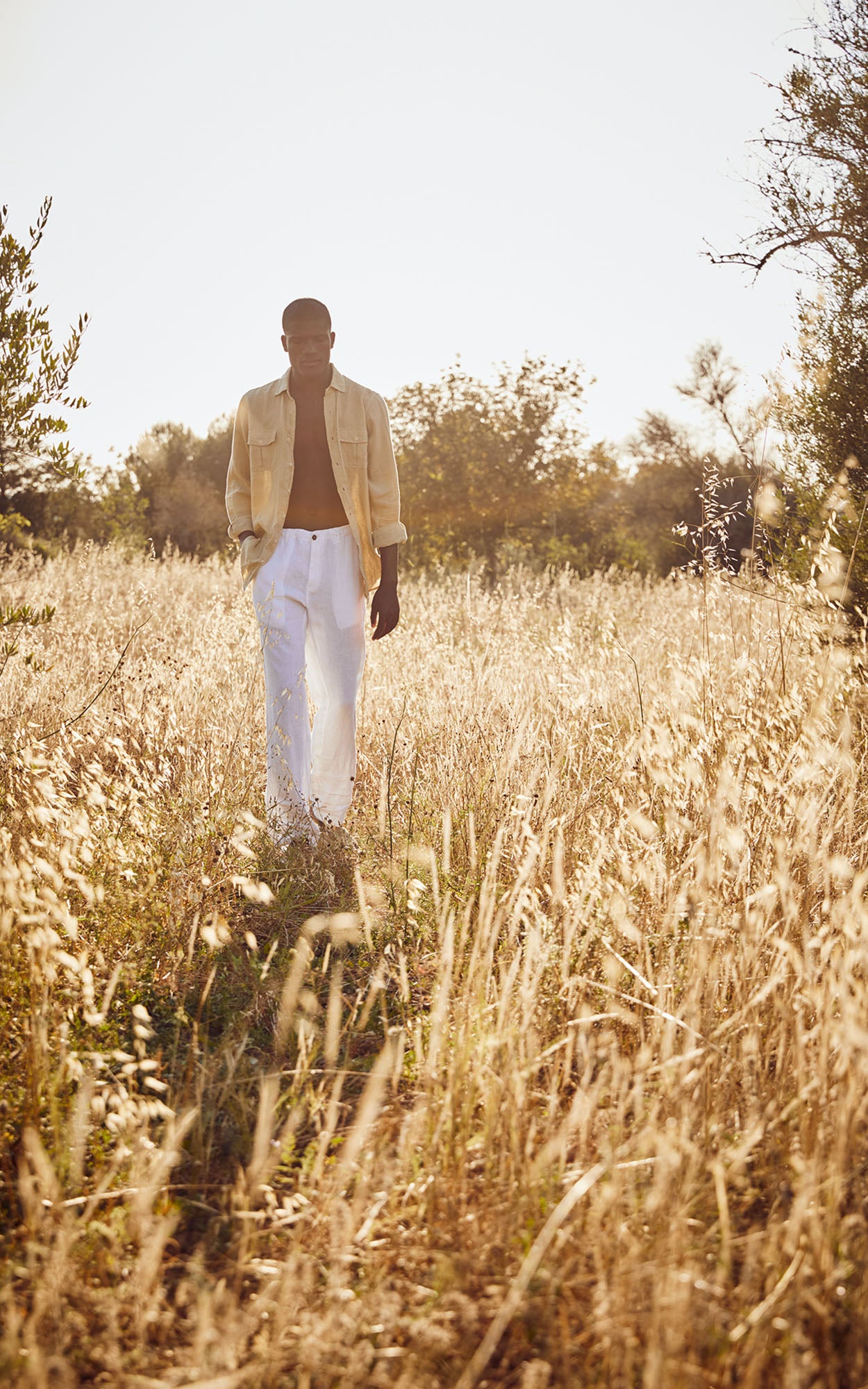model wears love brand & co designer linen clothing in a field of wheat.