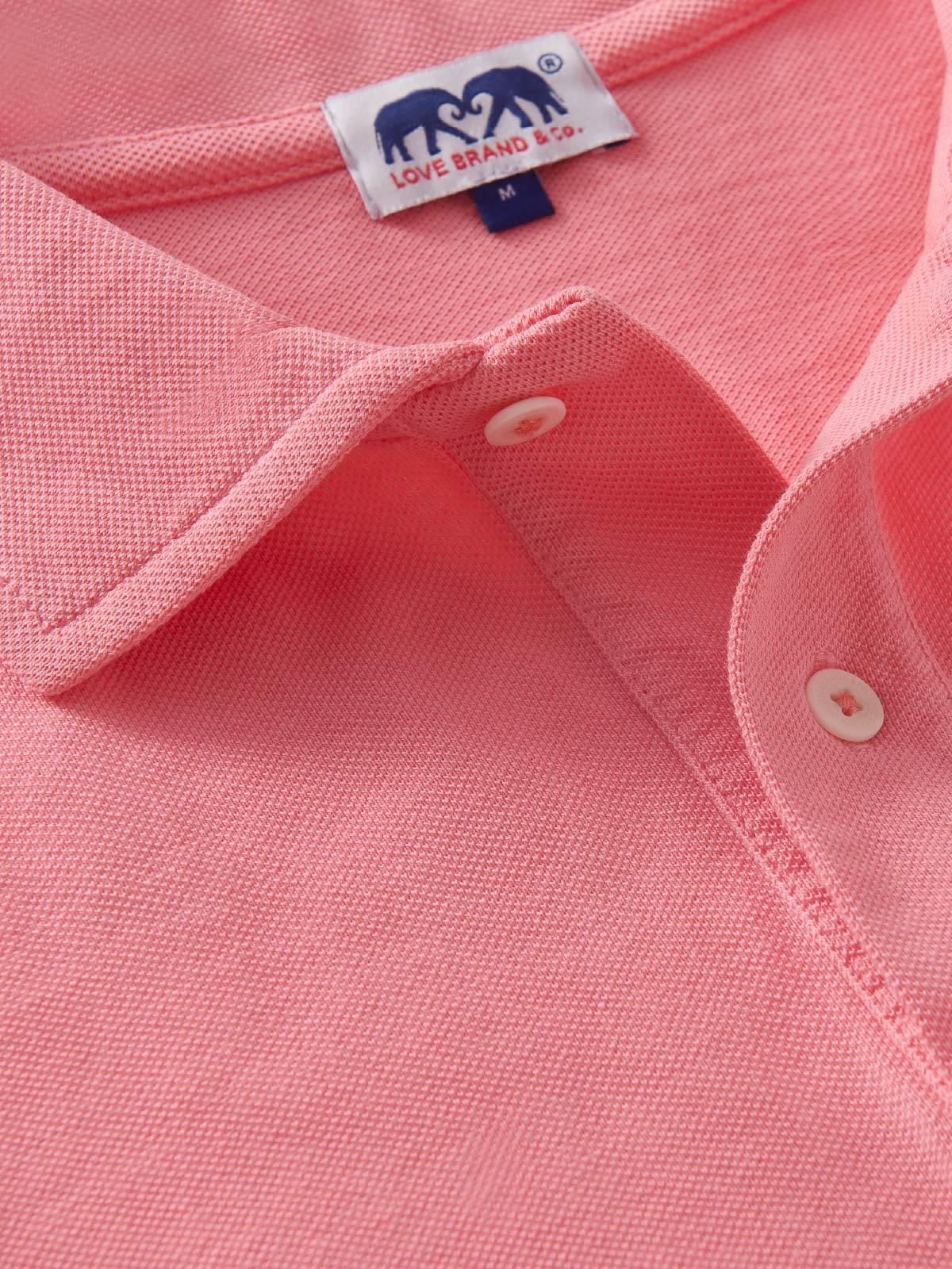 Close-up of a pink polo shirt with a love brand label on the collar.