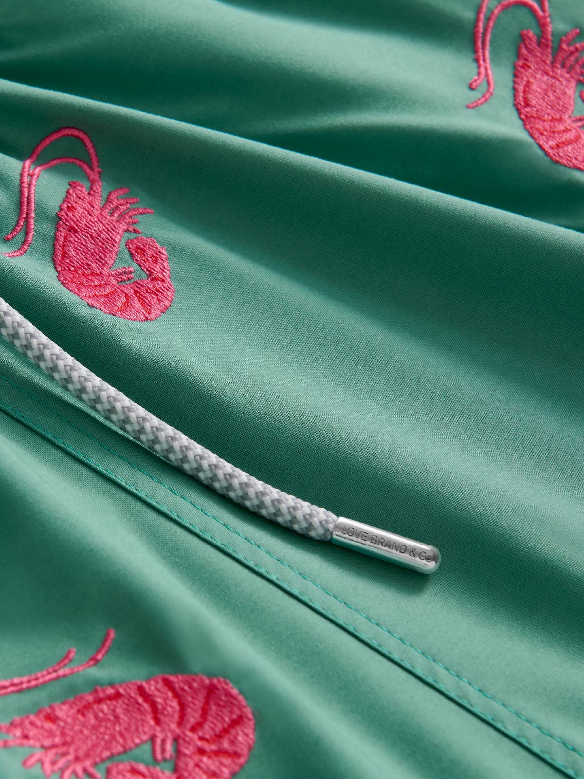 Green fabric with pink shrimp embroidery and a grey drawstring