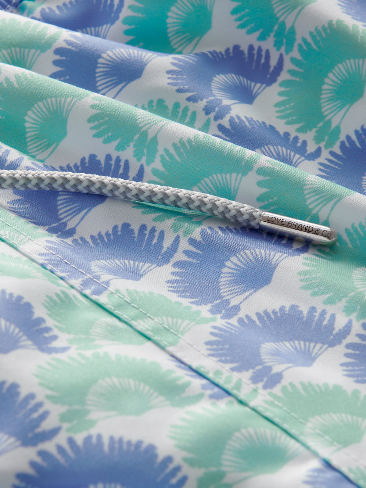 Close-up of a fabric with blue and green leaf pattern and a drawstring tie.
