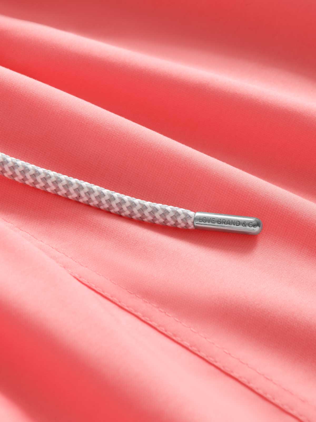 Close-up view of Men's Coral Rose Swim Shorts. Pink swim trunks for men with drawstring.