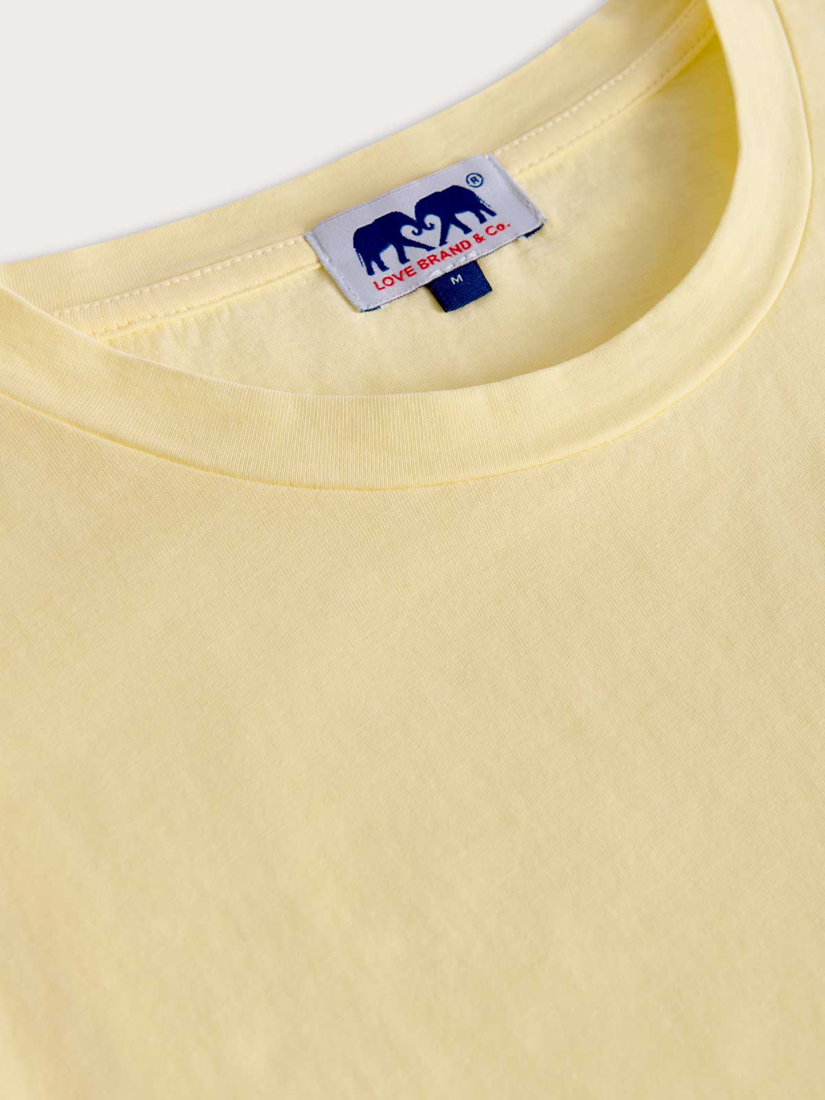 Close-up of a yellow t-shirt with a love brand label on a white background