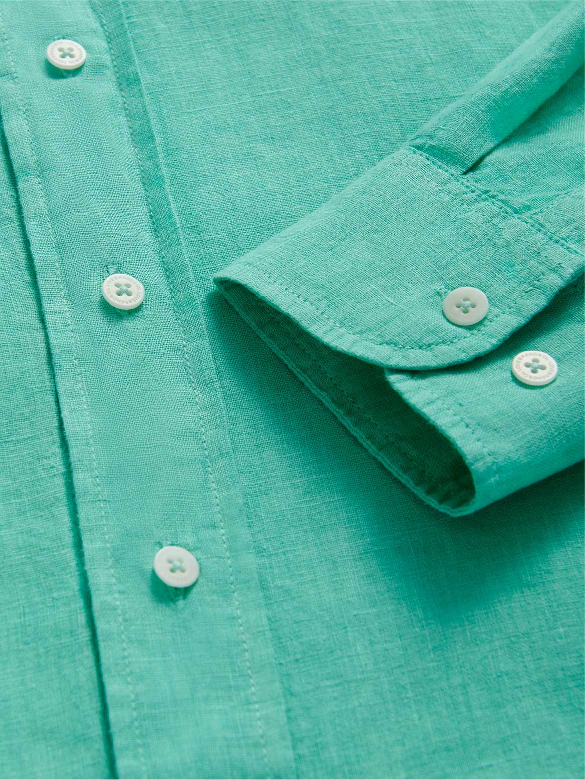 Close-up of a turquoise shirt with buttons and a rolled-up sleeve.