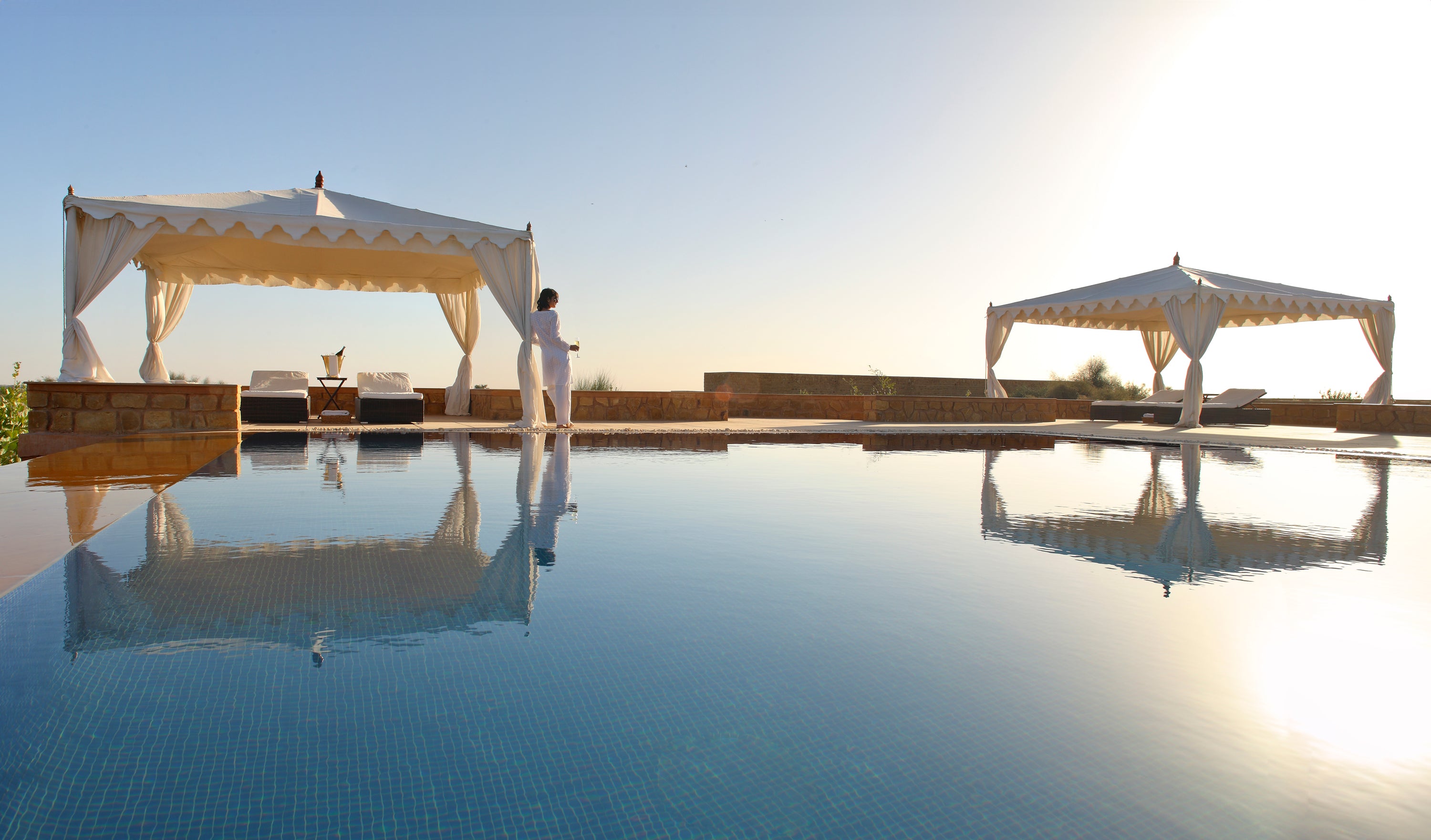 Two white tents by a pool with a clear blue sky at SUJÁN Serai