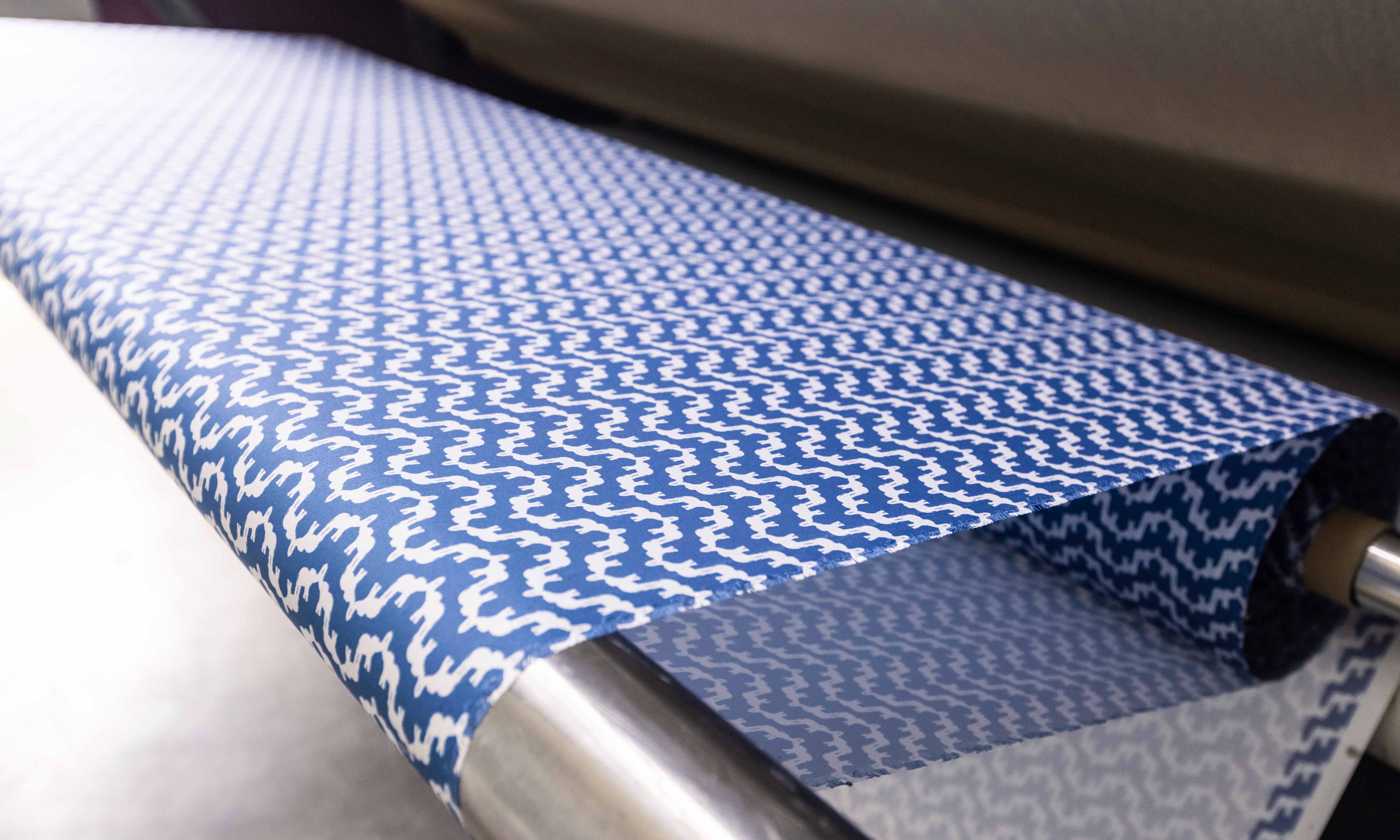 Roll of blue and white patterned fabric in a printing machine.