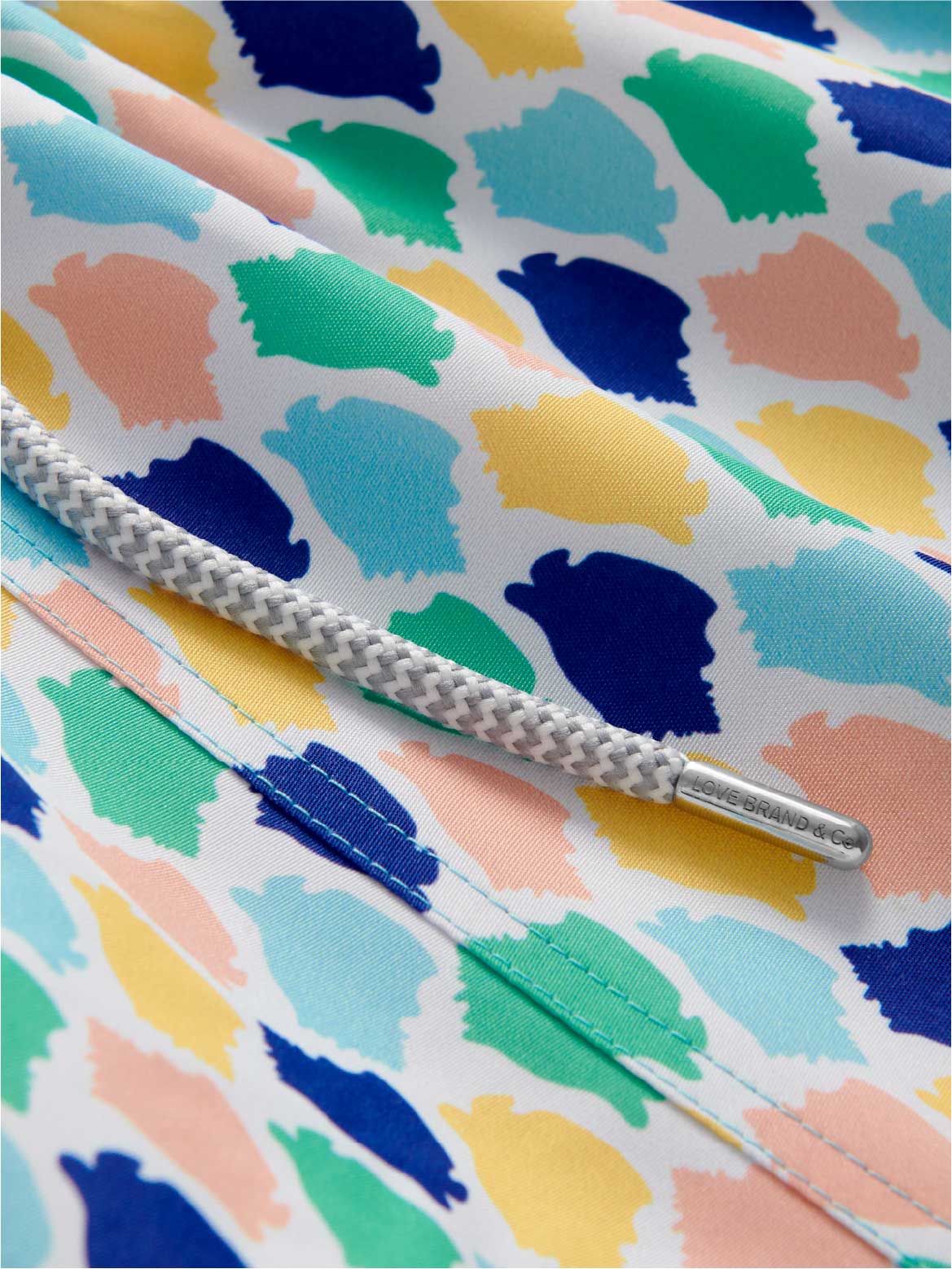 Detailed view of mens swim trunks showing drawstring and colourful conch shell pattern.