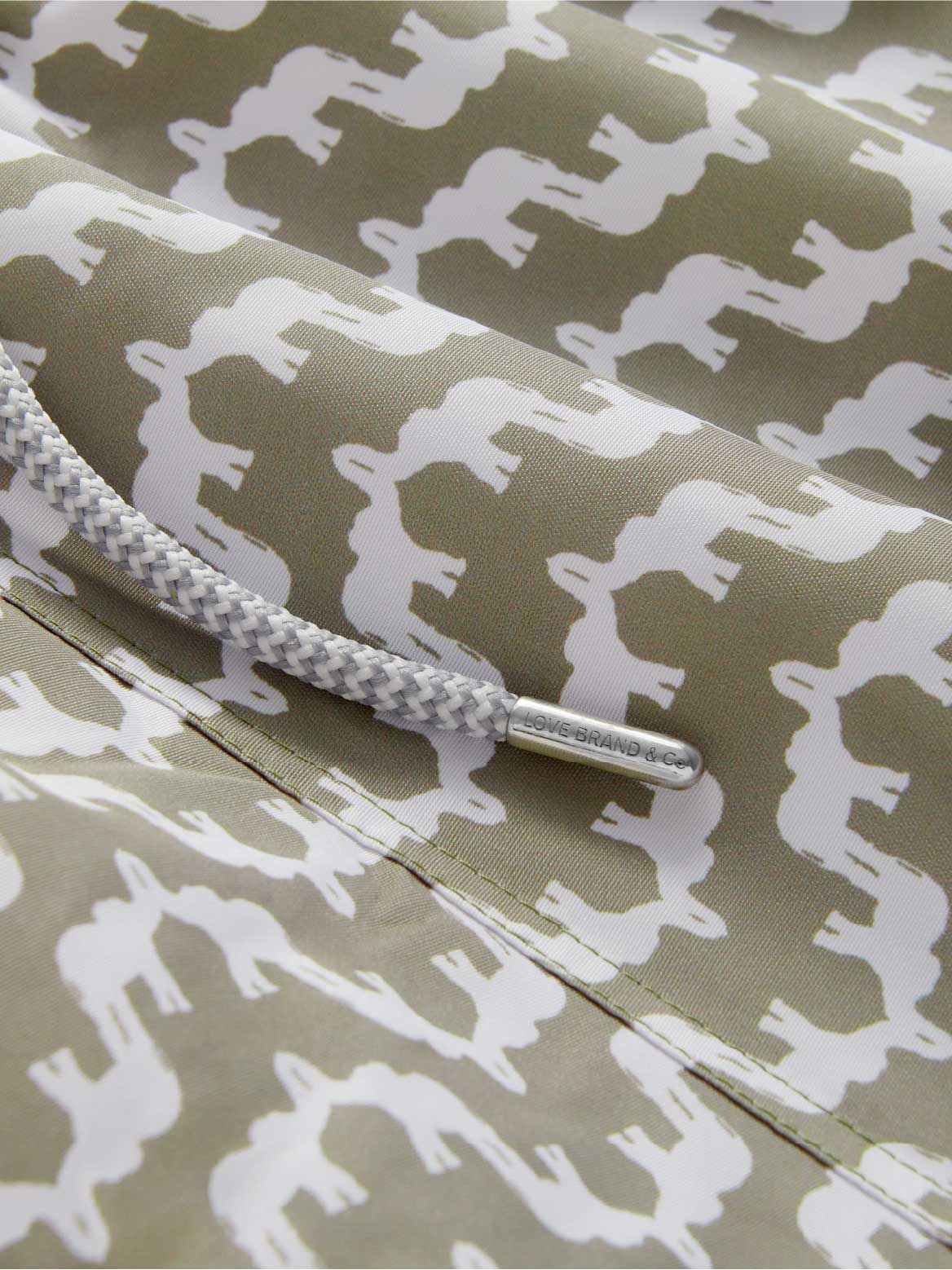 Close-up view of swimming trunks showing drawstring and green elephant pattern.