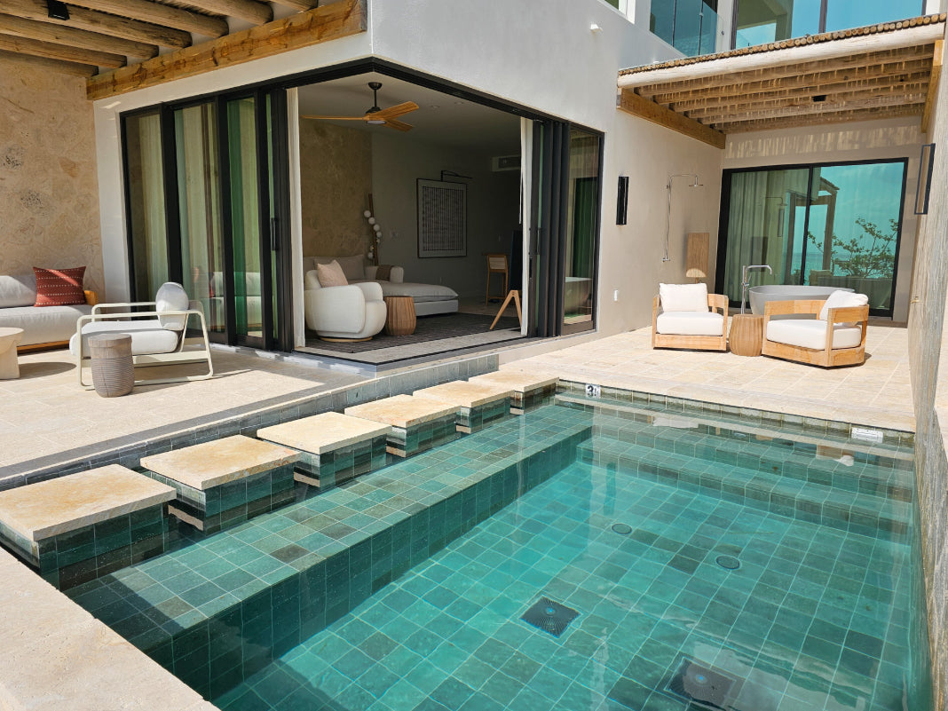 Modern outdoor area at The Strand Turks & Caicos with a pool, lounge chairs, and a view into a living room.