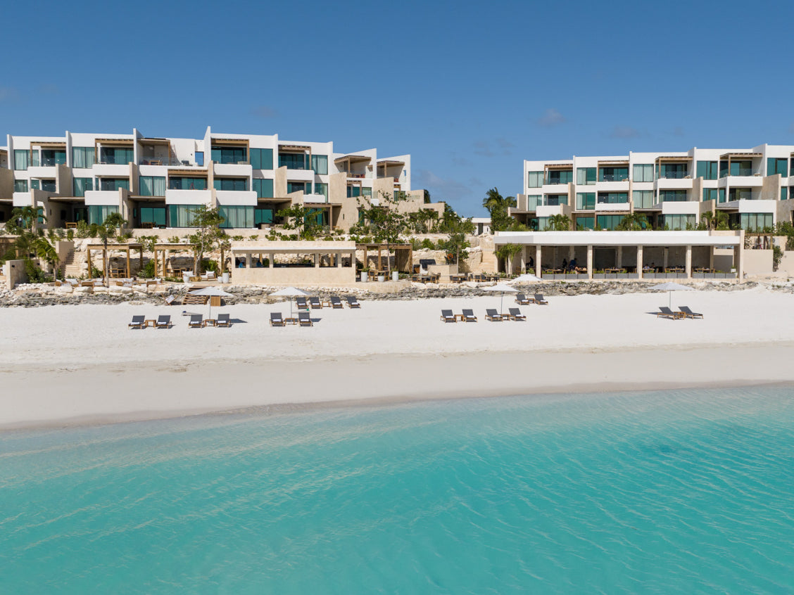 Beachfront resort with modern buildings and clear blue water.