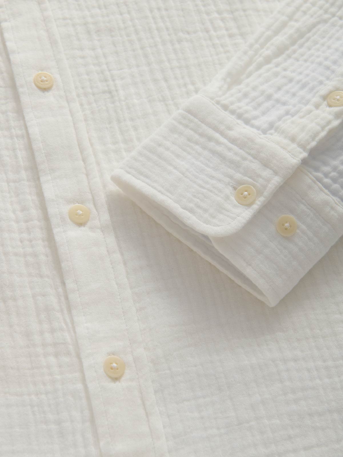 Close-up of a white textured shirt with button details