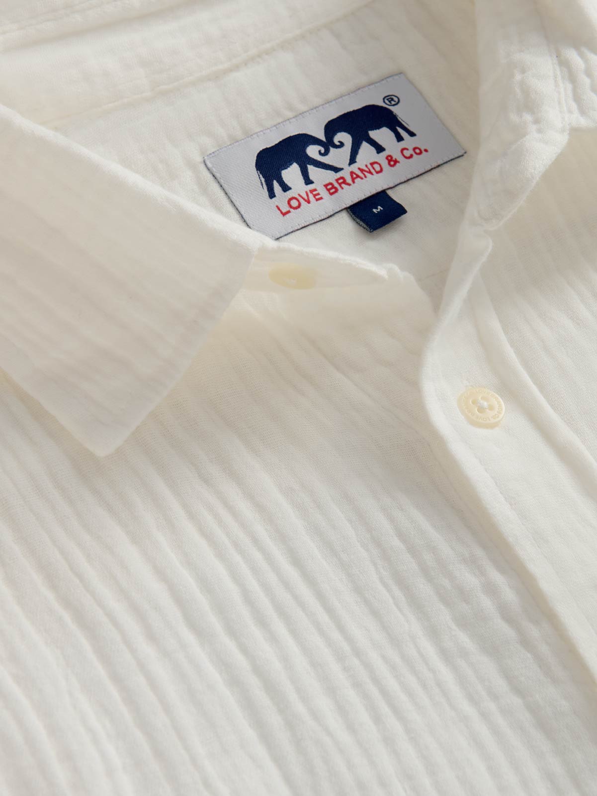 Close-up of a white shirt with a brand label featuring two elephants.