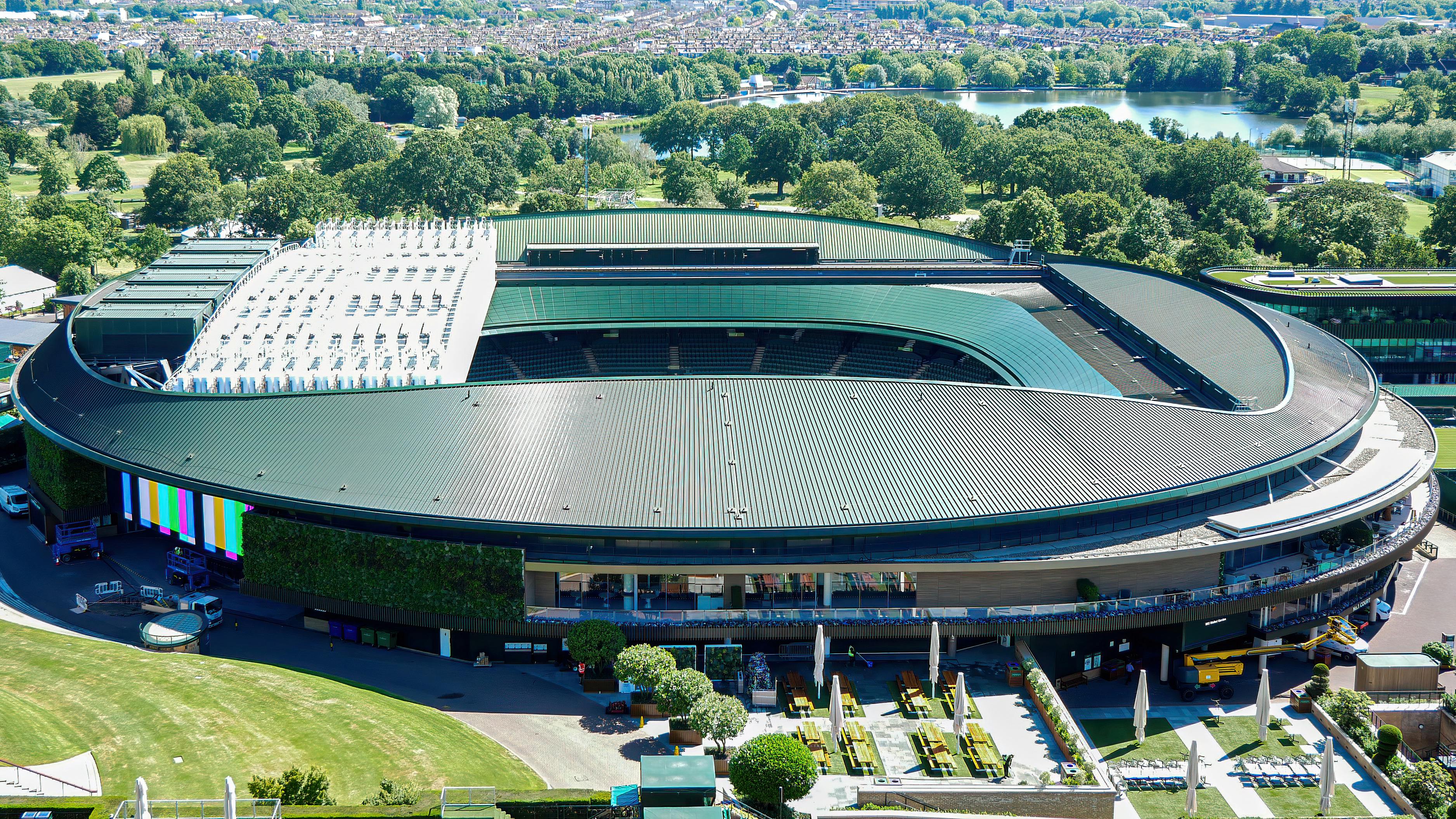 Aerial view of wimbledon stadium with a green roof, surrounded by trees and open spaces.