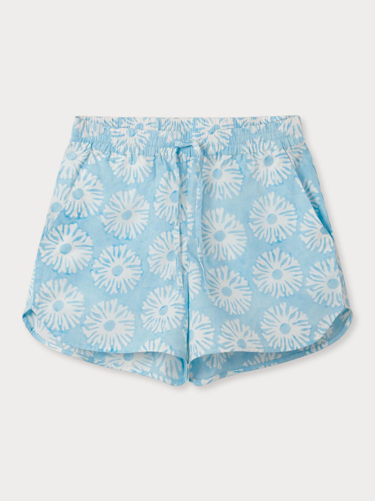 Blue shorts with white floral coral pattern on a light grey background.