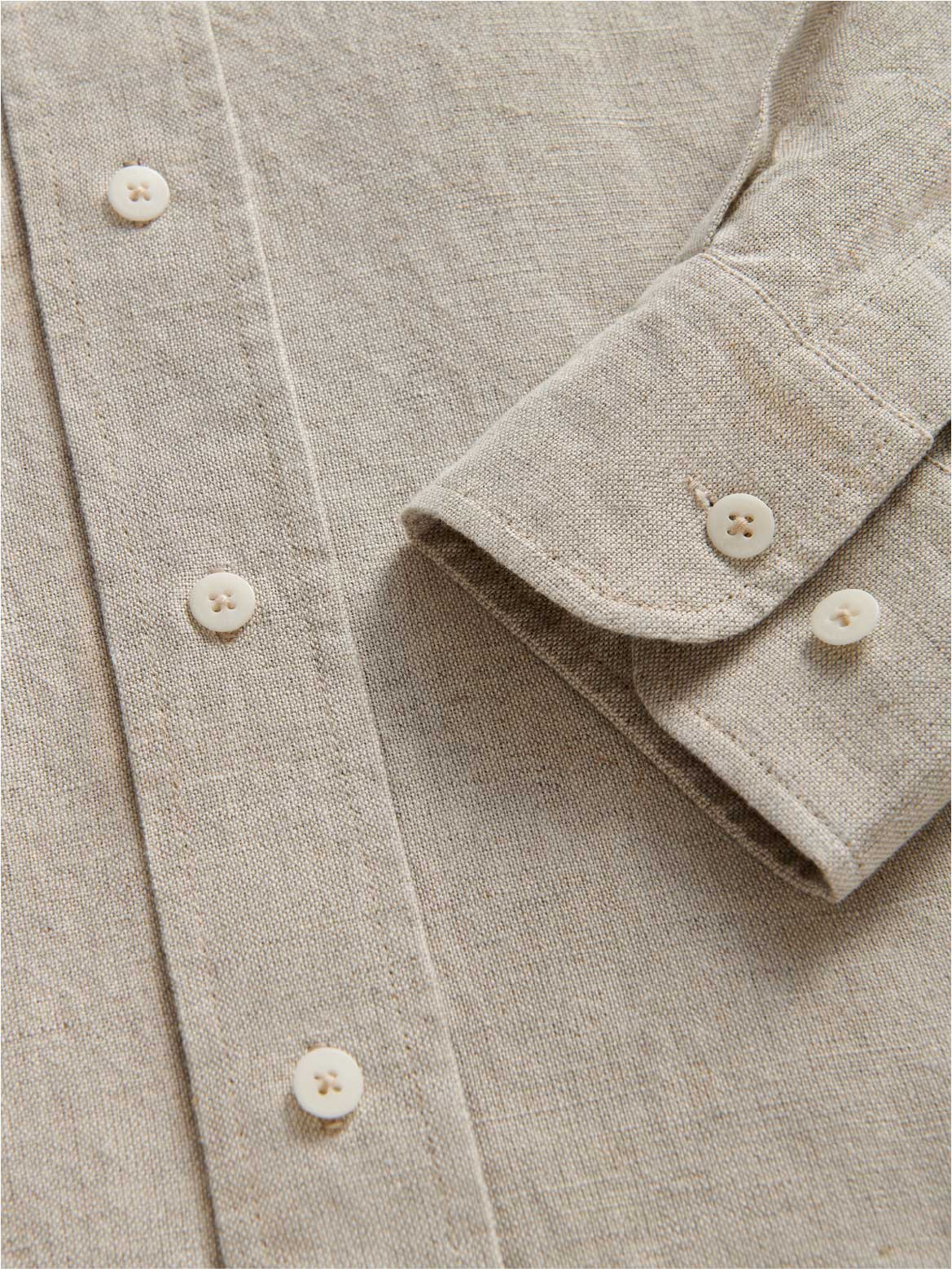 Close-up of a beige shirt dress with buttons and folded sleeve.