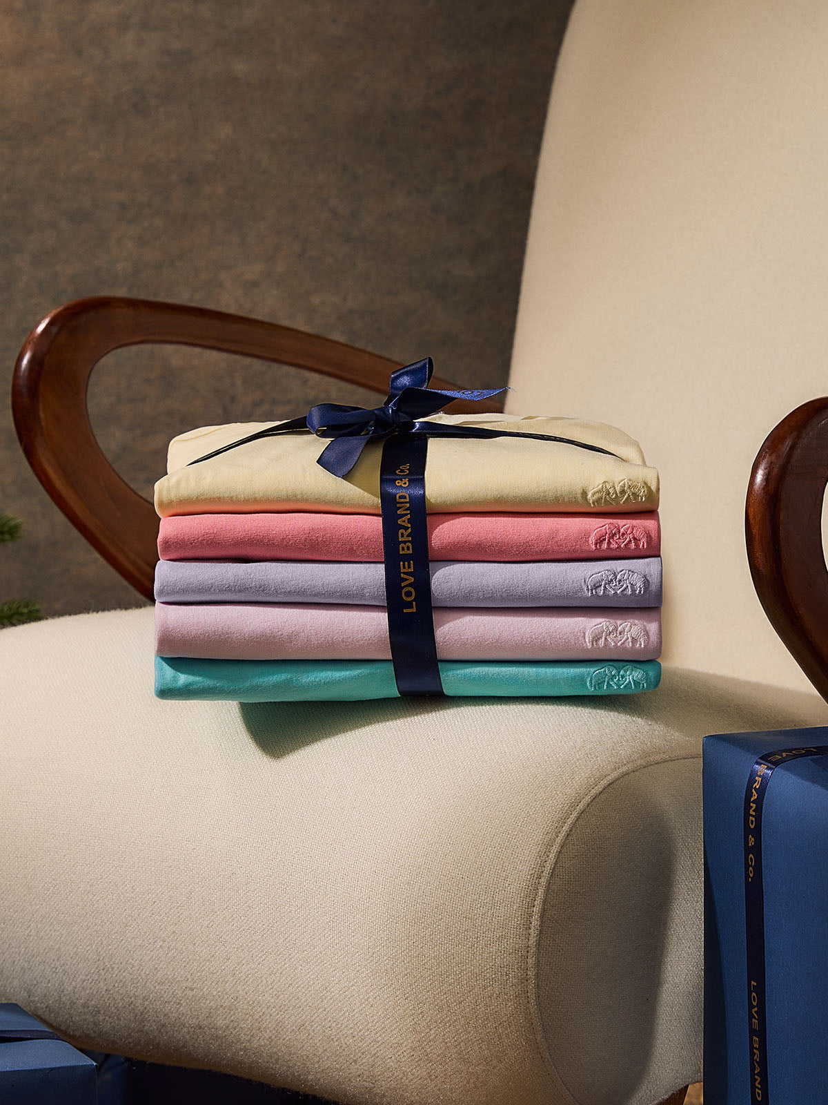 Stack of folded t-shirts with a blue ribbon on a chair