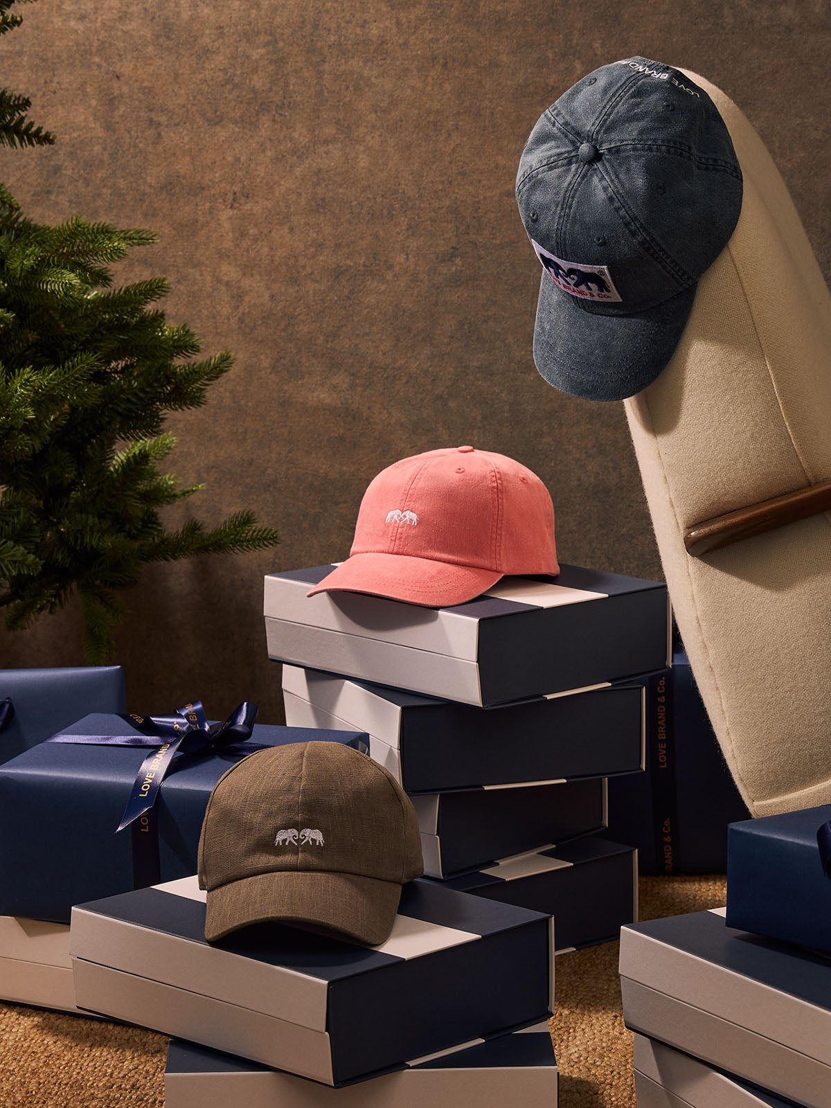 Three baseball caps in different colors on display with packaging boxes against a textured wall.