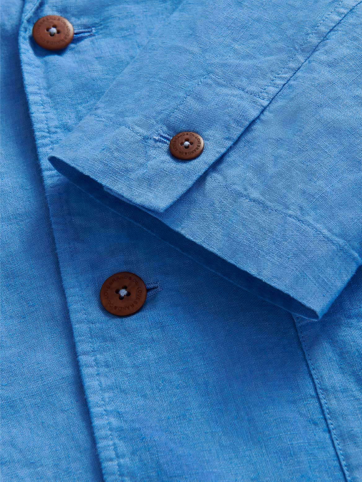 Close-up of a blue linen jacket with brown buttons.